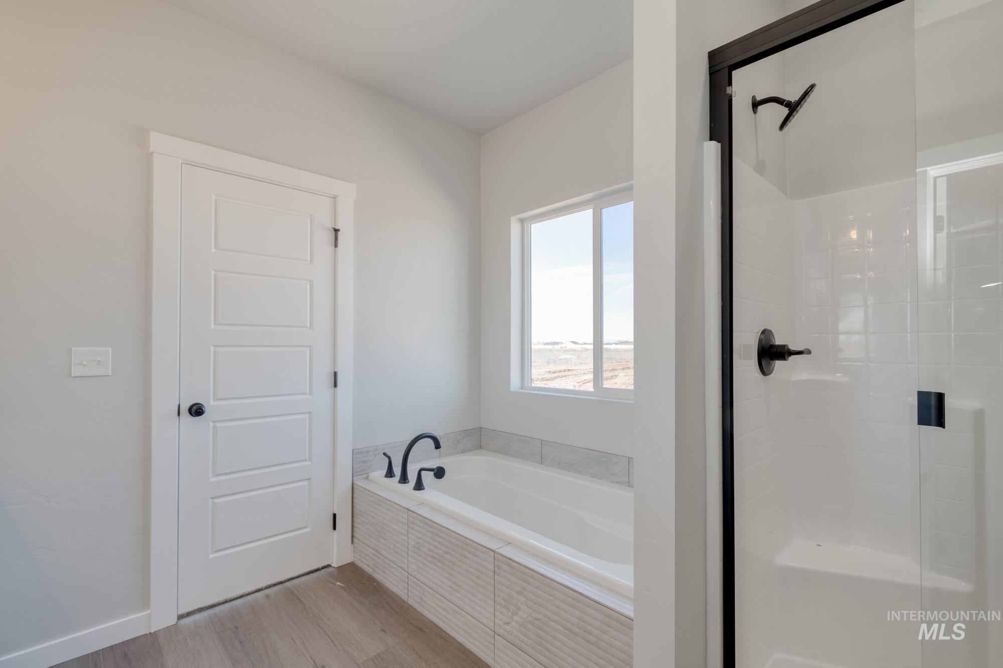 Full bathroom featuring a shower stall, light wood-style floors, and a garden tub