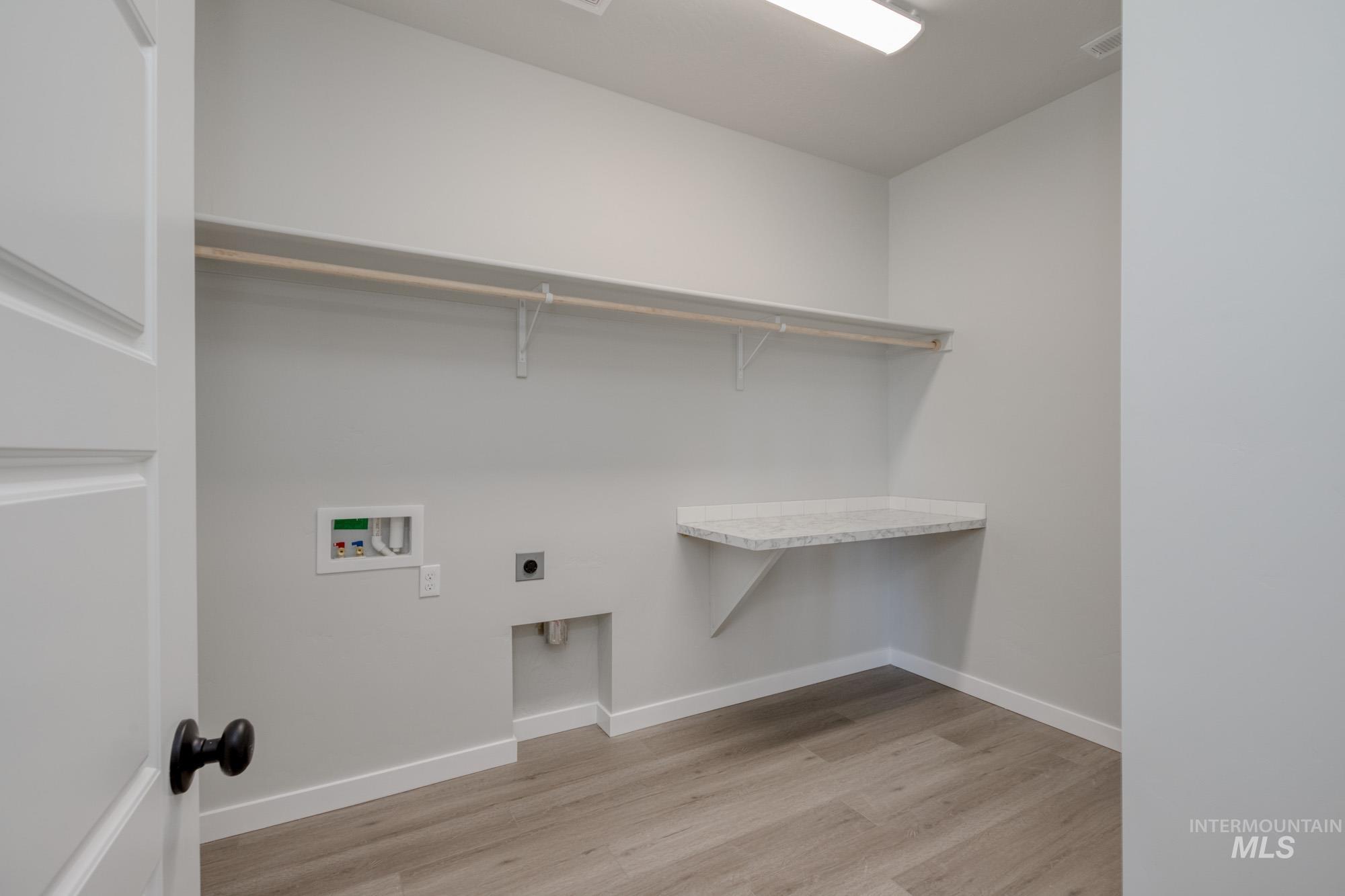 Laundry area featuring light wood-style floors, electric dryer hookup, and washer hookup