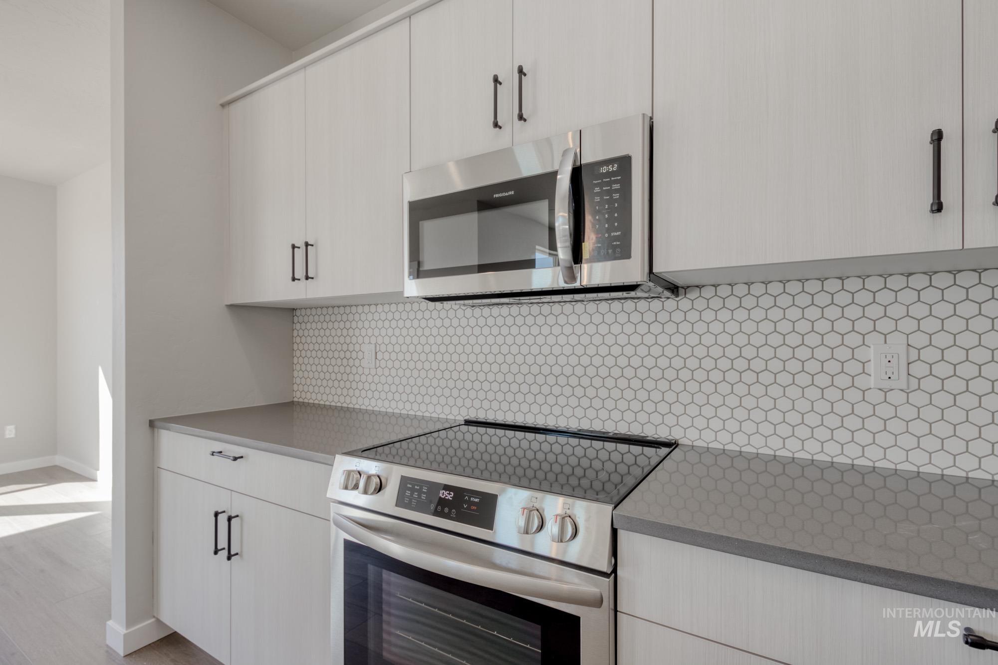 Kitchen with appliances with stainless steel finishes, backsplash, light wood-type flooring, and modern cabinets