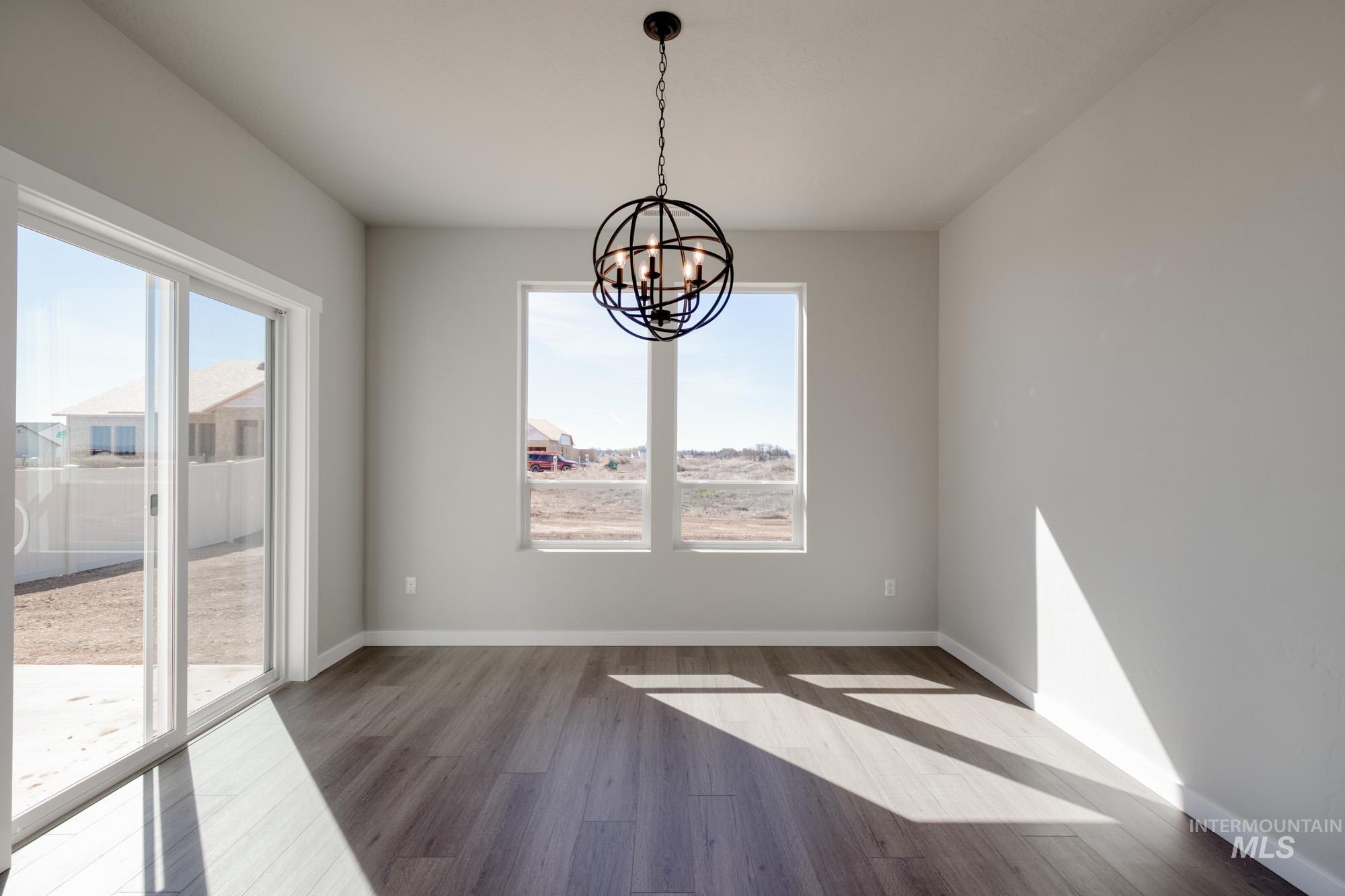 Unfurnished dining area with wood finished floors and a chandelier