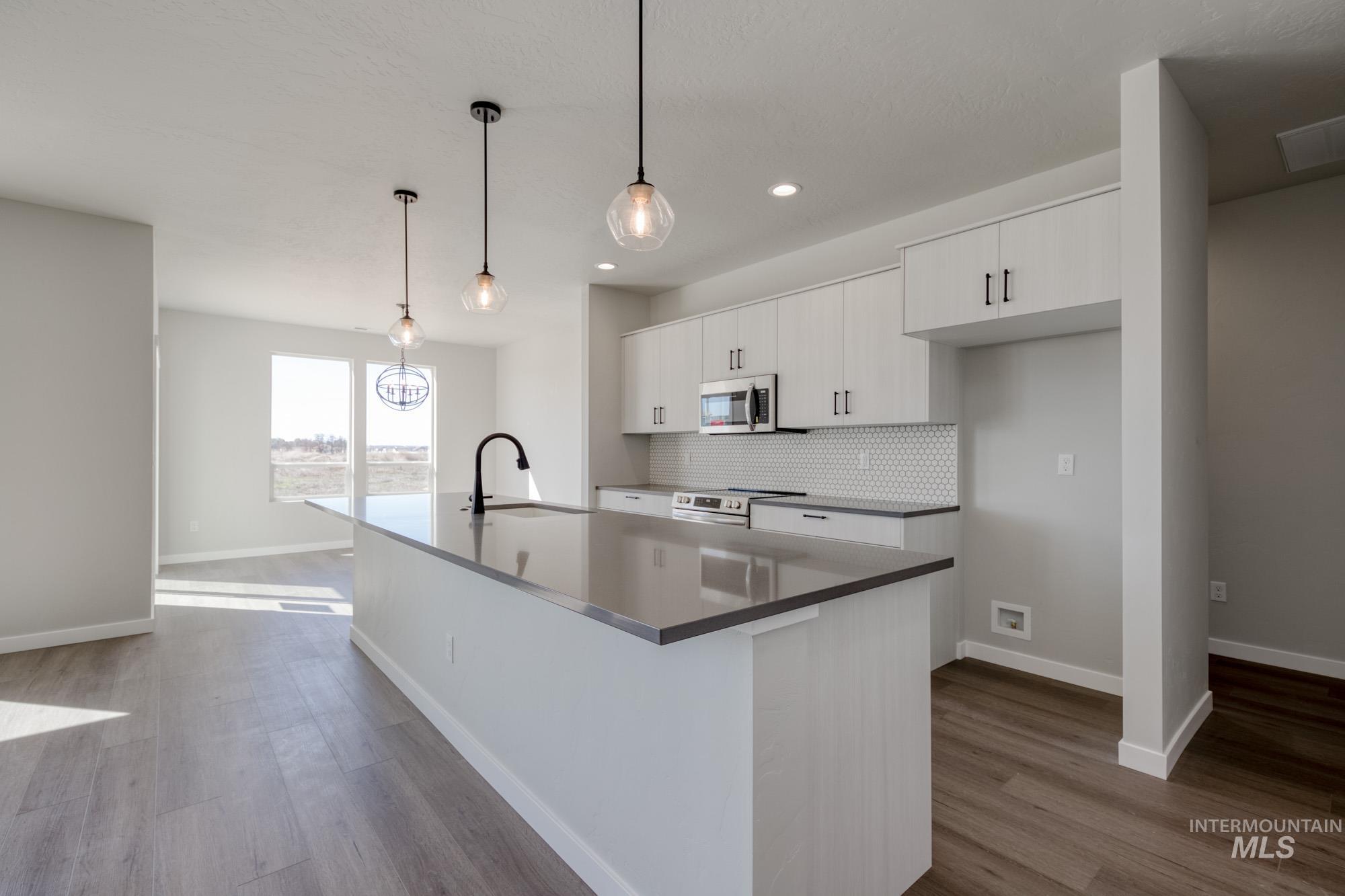 Kitchen featuring white cabinetry, backsplash, decorative light fixtures, dark wood-style floors, and recessed lighting