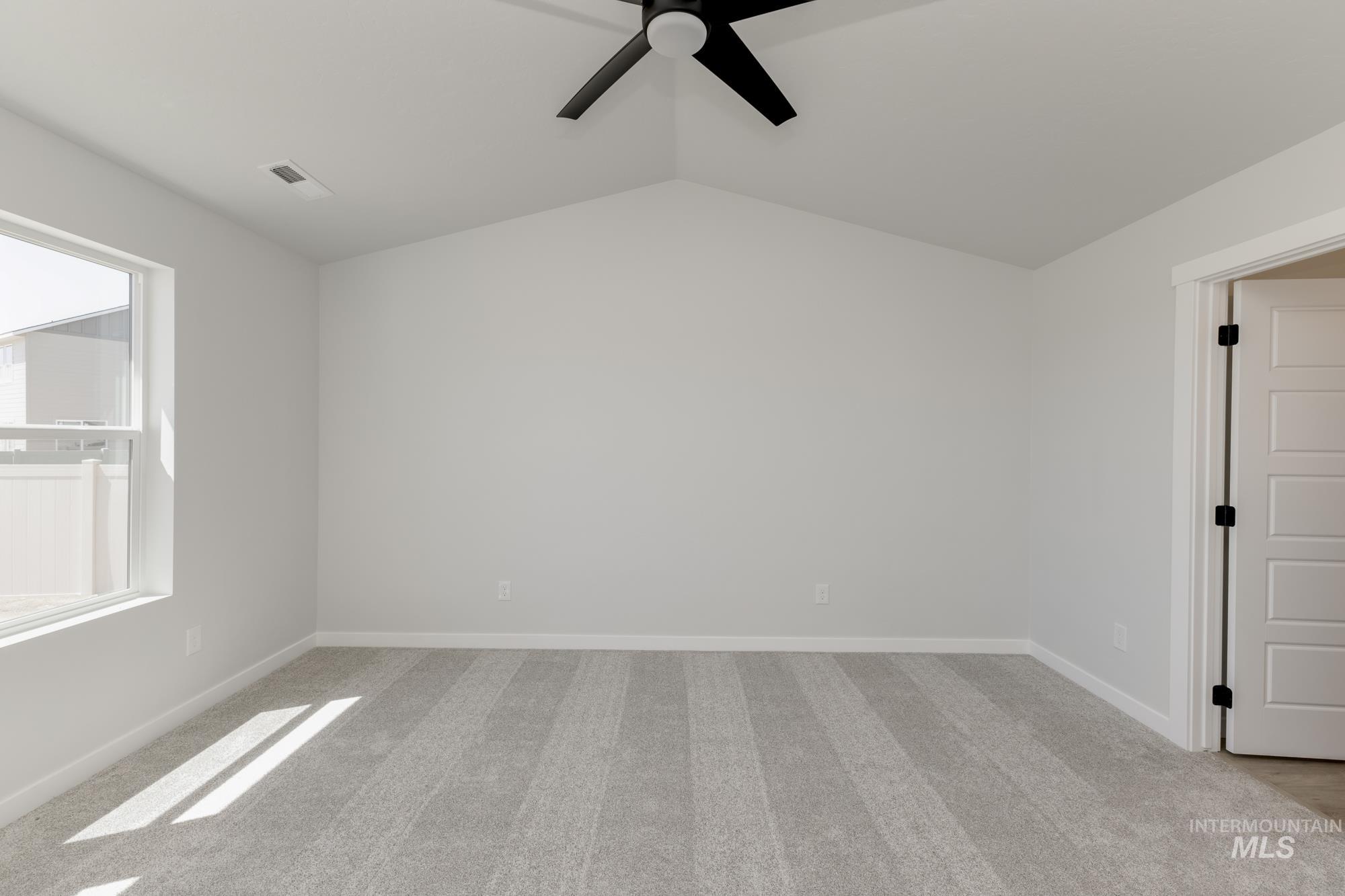 Spare room featuring light carpet, a ceiling fan, and vaulted ceiling