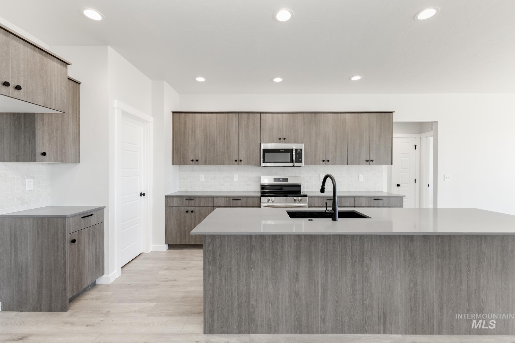 Kitchen featuring appliances with stainless steel finishes, tasteful backsplash, recessed lighting, and light stone counters
