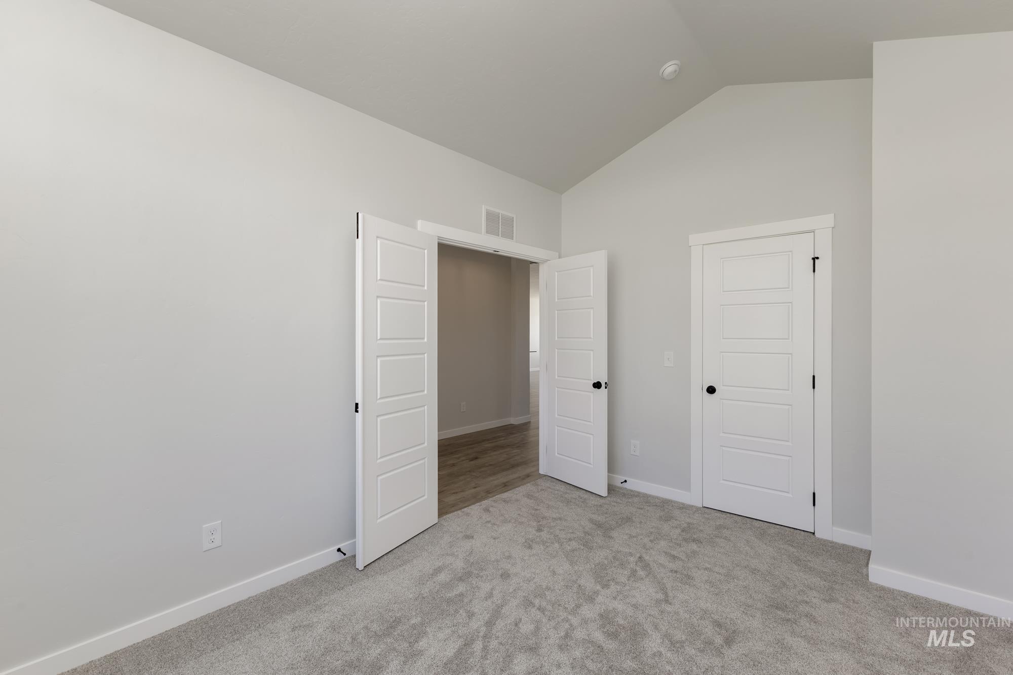 Unfurnished bedroom with carpet flooring and high vaulted ceiling