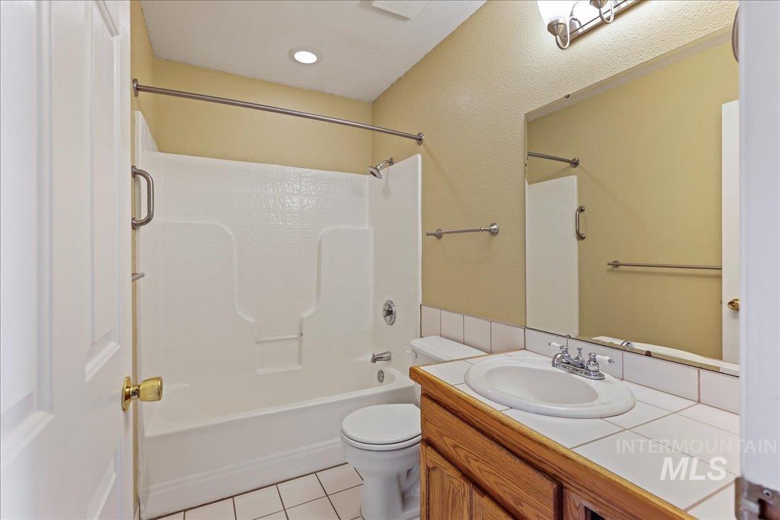 Full bath with light tile patterned floors, vanity, and shower / bathtub combination