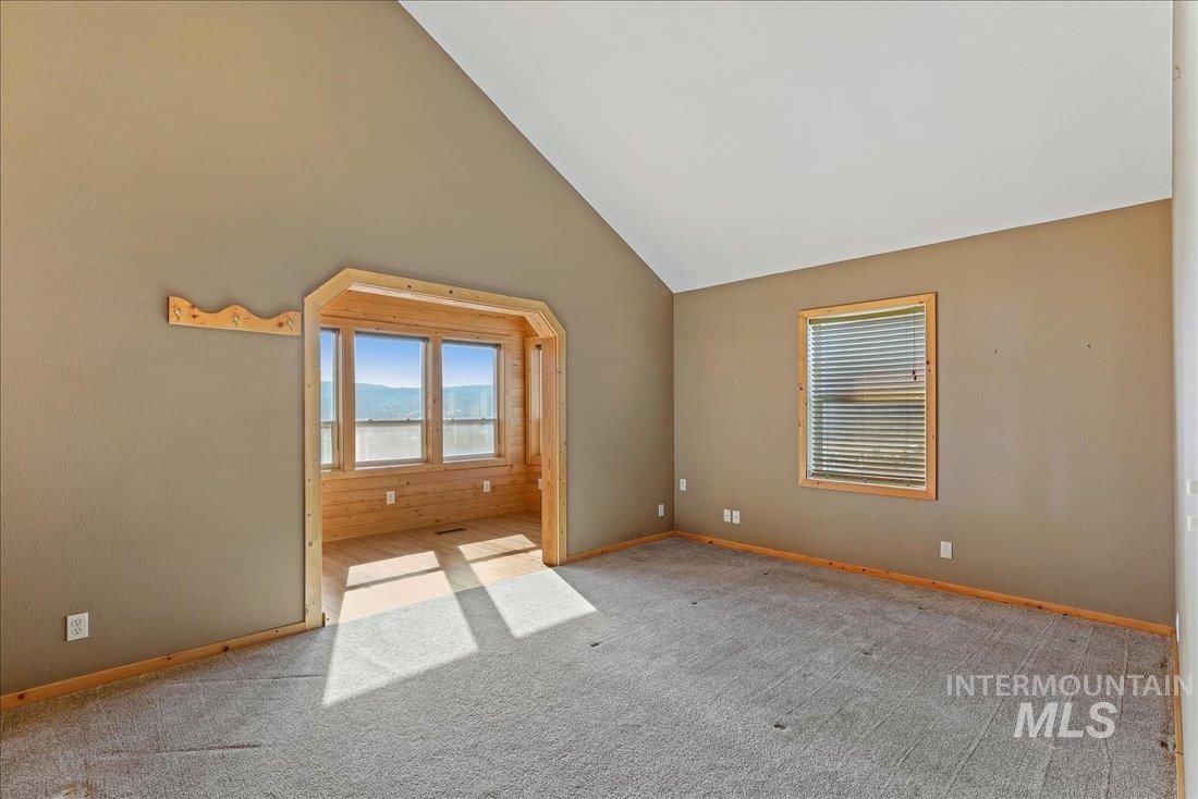 Empty room with carpet flooring and high vaulted ceiling