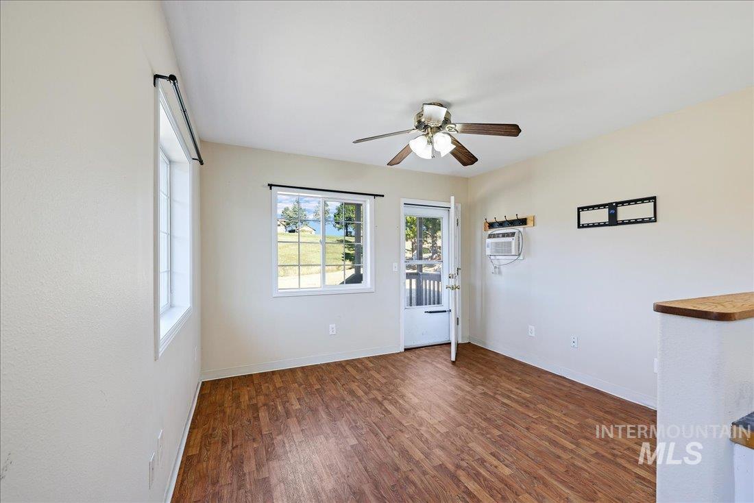 Spare room featuring dark wood finished floors, ceiling fan, and a wall mounted AC