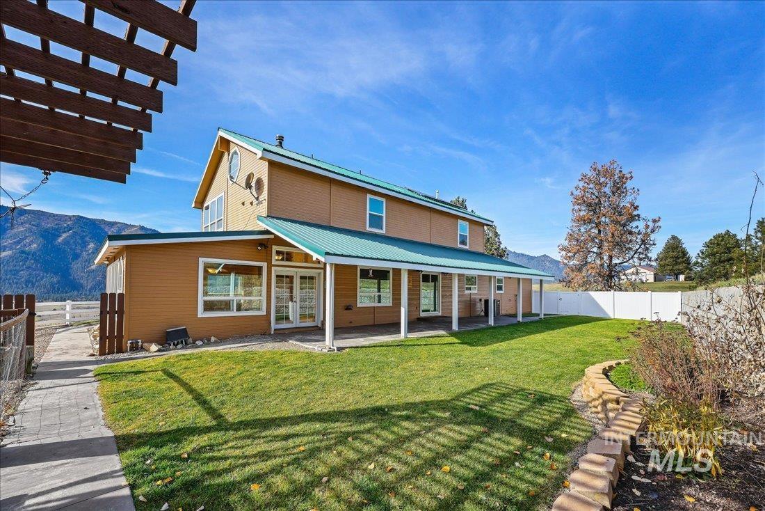 Rear view of house with french doors, a patio, a fenced backyard, and a mountain view