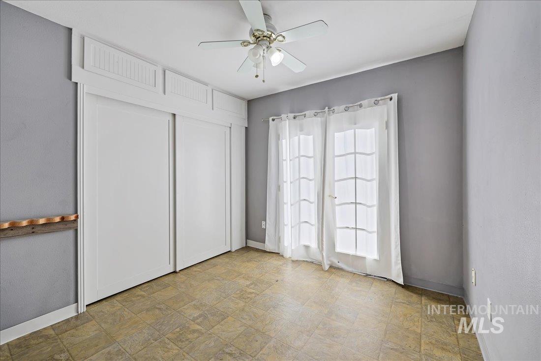 Unfurnished bedroom featuring ceiling fan, a closet, and stone finish flooring