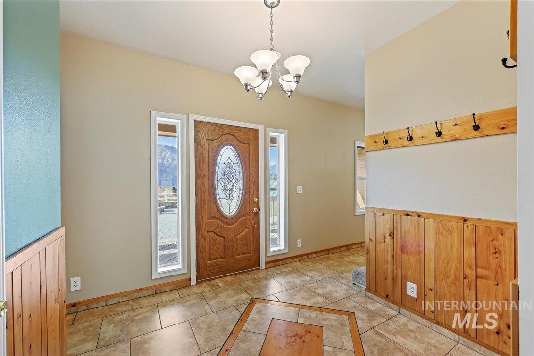 Entryway with light tile patterned floors, a chandelier, wood walls, and inlaid floor details
