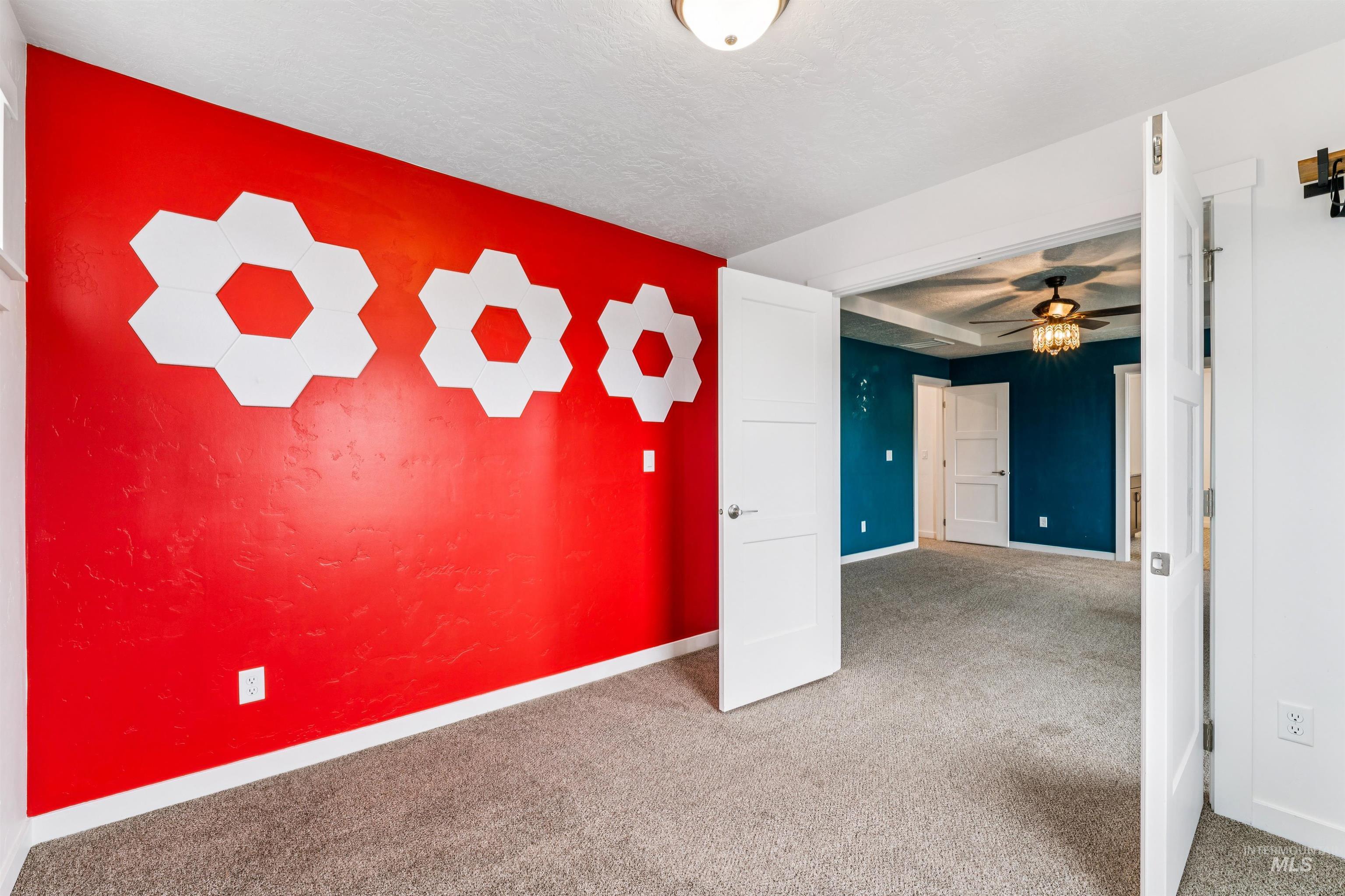 Empty room featuring carpet, ceiling fan, a textured ceiling, and a textured wall