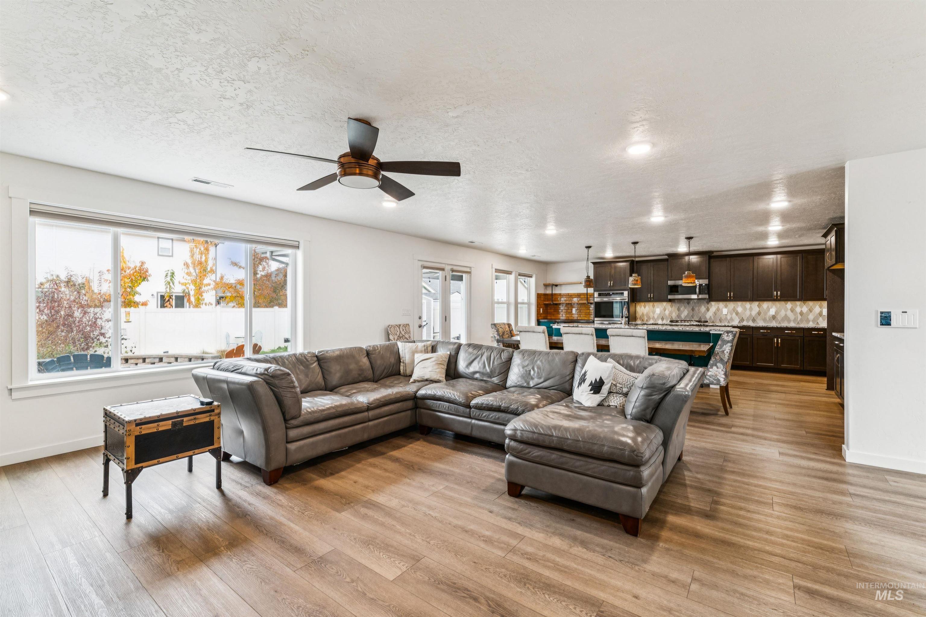 Living room with plenty of natural light, a textured ceiling, light wood finished floors, recessed lighting, and a ceiling fan