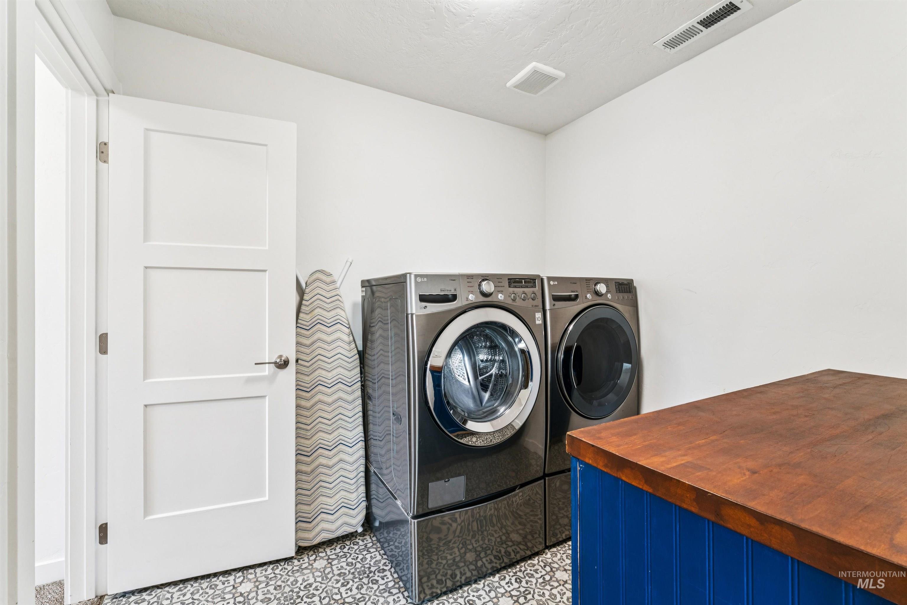 Washroom featuring washing machine and dryer and a textured ceiling