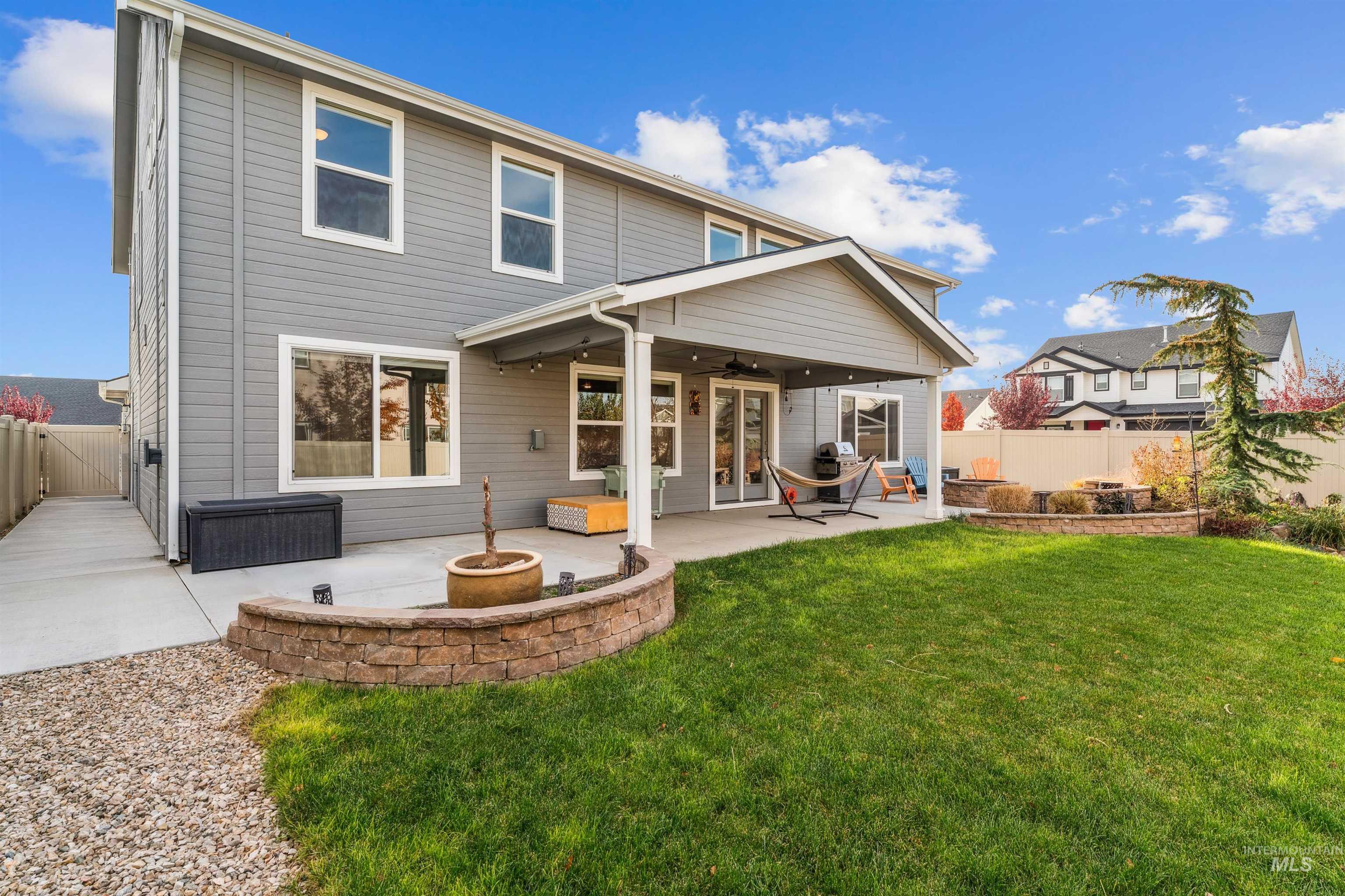 Rear view of house with ceiling fan, a fenced backyard, a fire pit, a patio area, and french doors