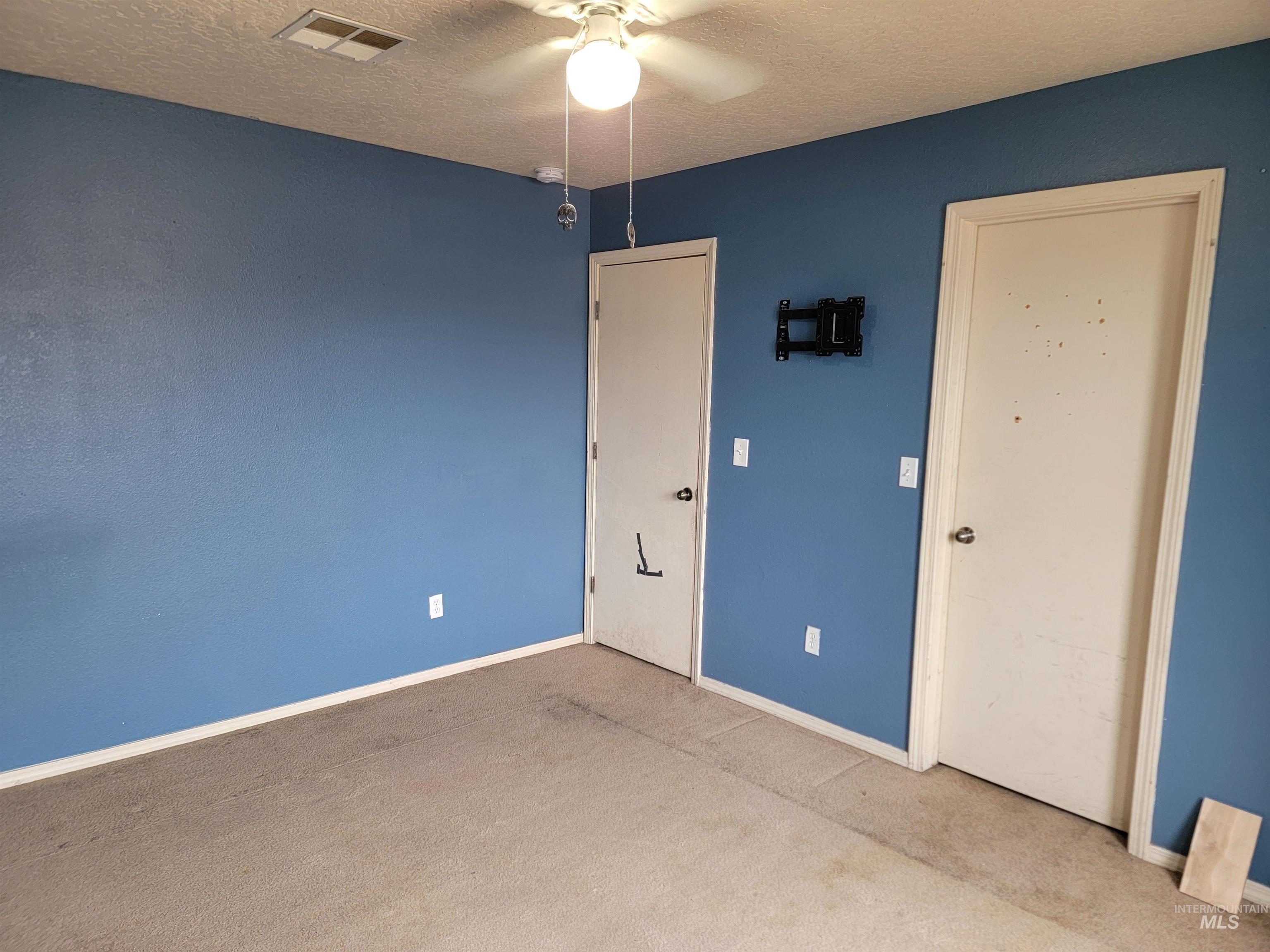Unfurnished room featuring a textured ceiling, a ceiling fan, and carpet floors