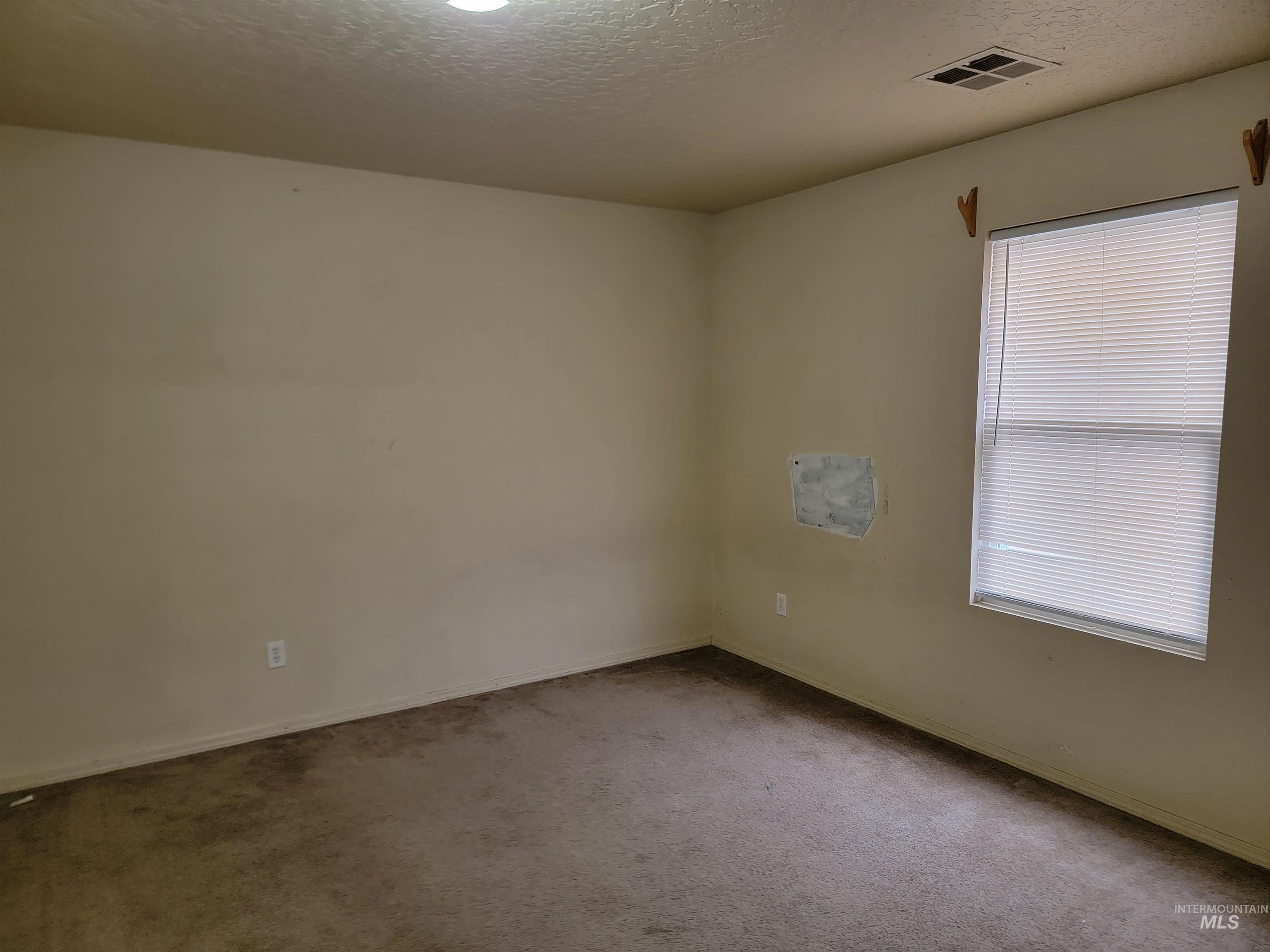 Unfurnished room featuring a textured ceiling and carpet flooring