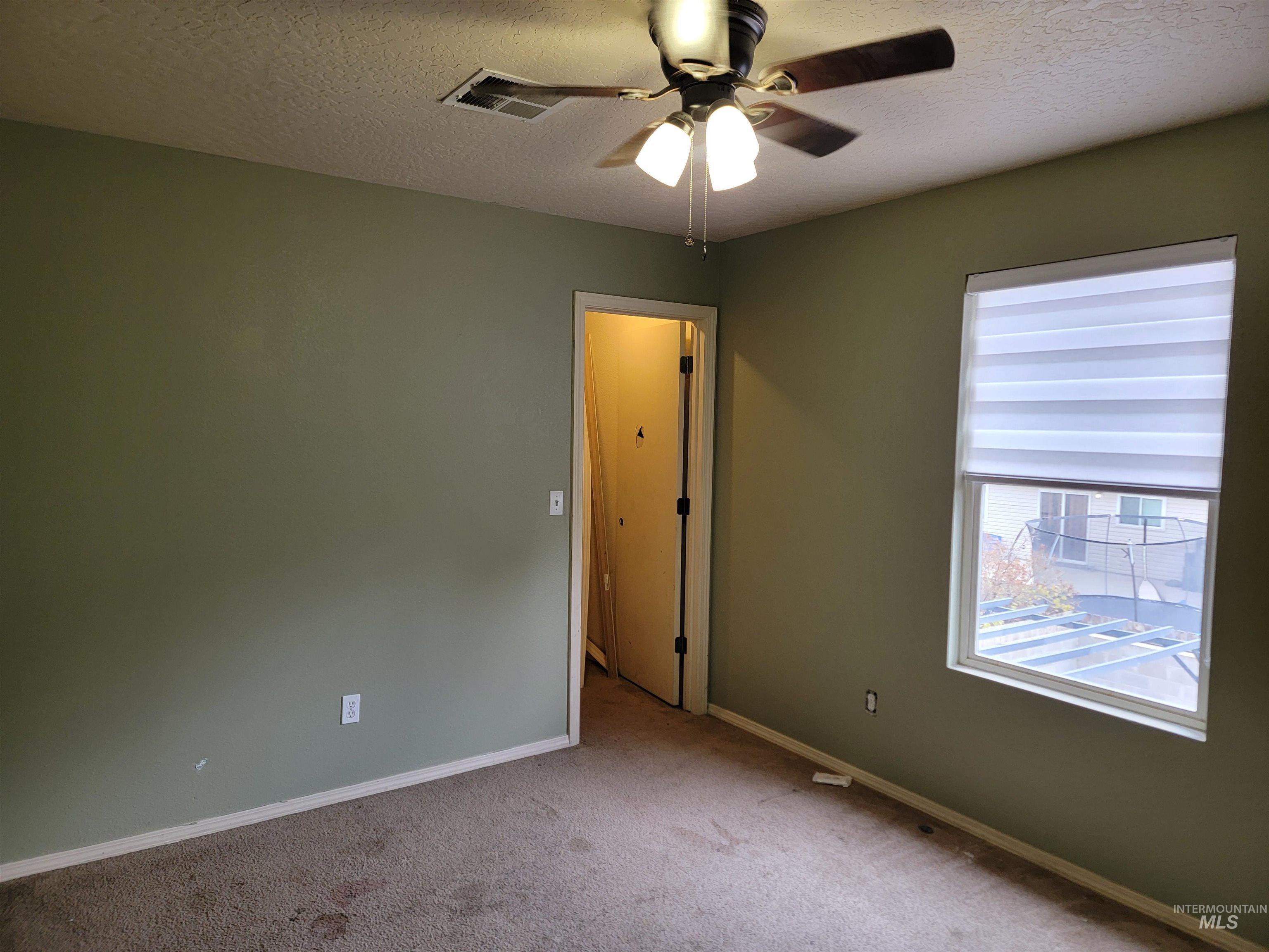 Unfurnished room with a textured ceiling, carpet, and a ceiling fan