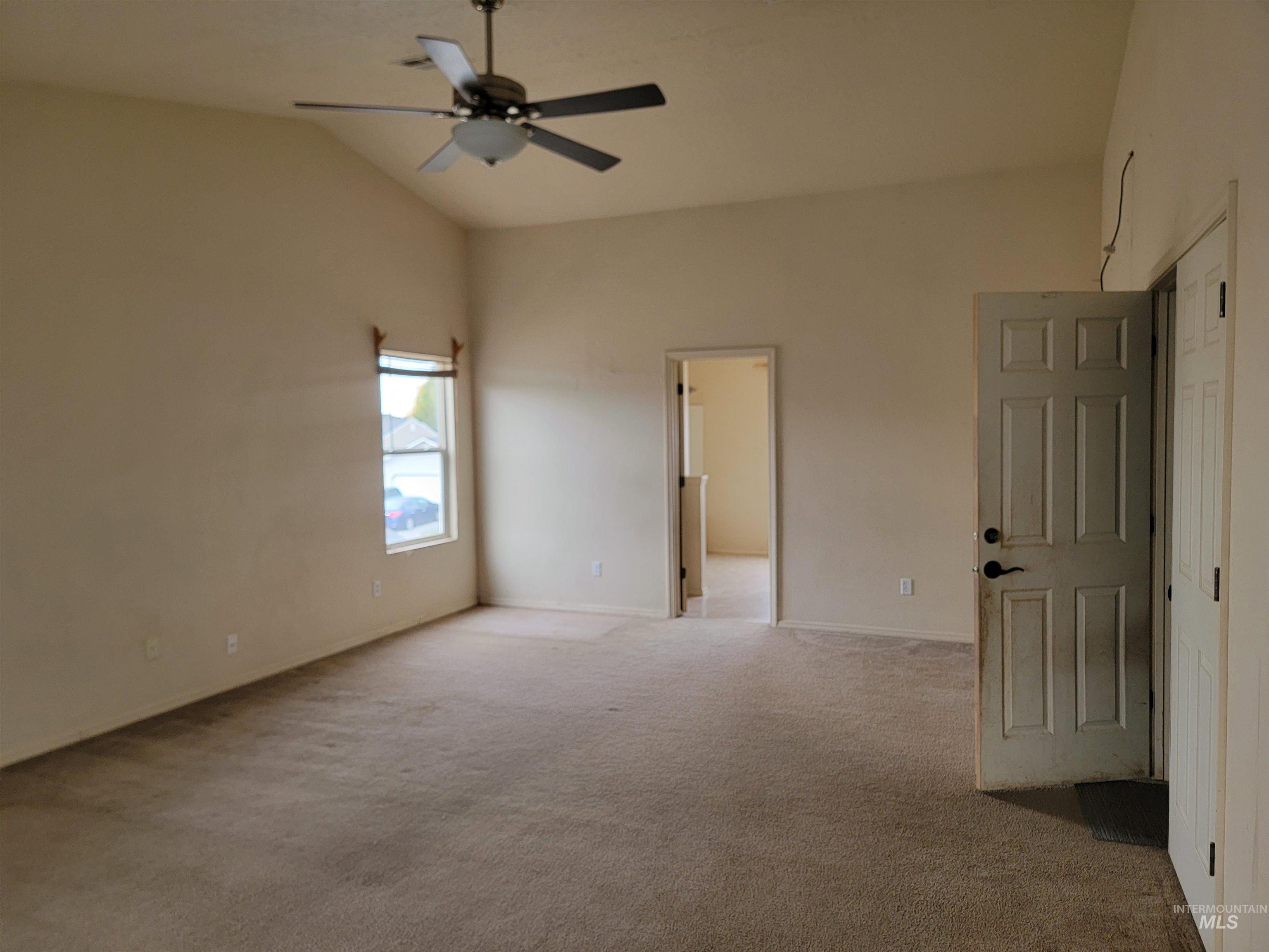 Unfurnished room with lofted ceiling, light carpet, and a ceiling fan