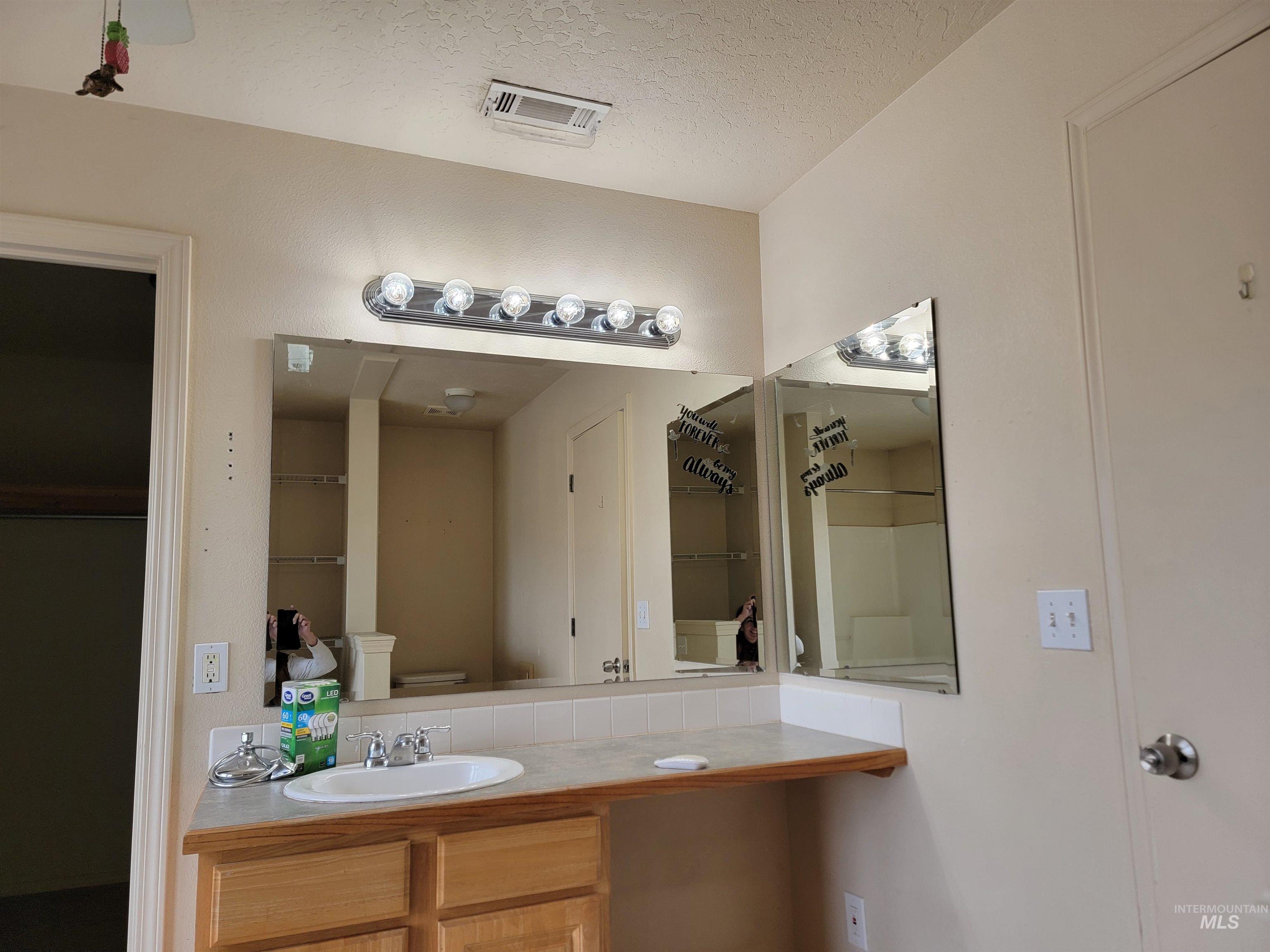 Full bath with vanity and a textured ceiling