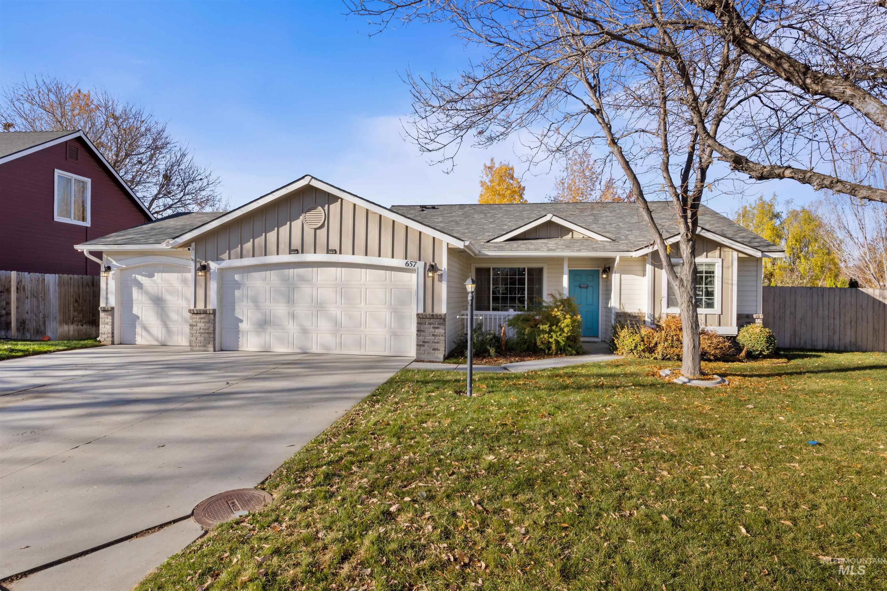 Ranch-style home featuring an attached garage, board and batten siding, driveway, and roof with shingles