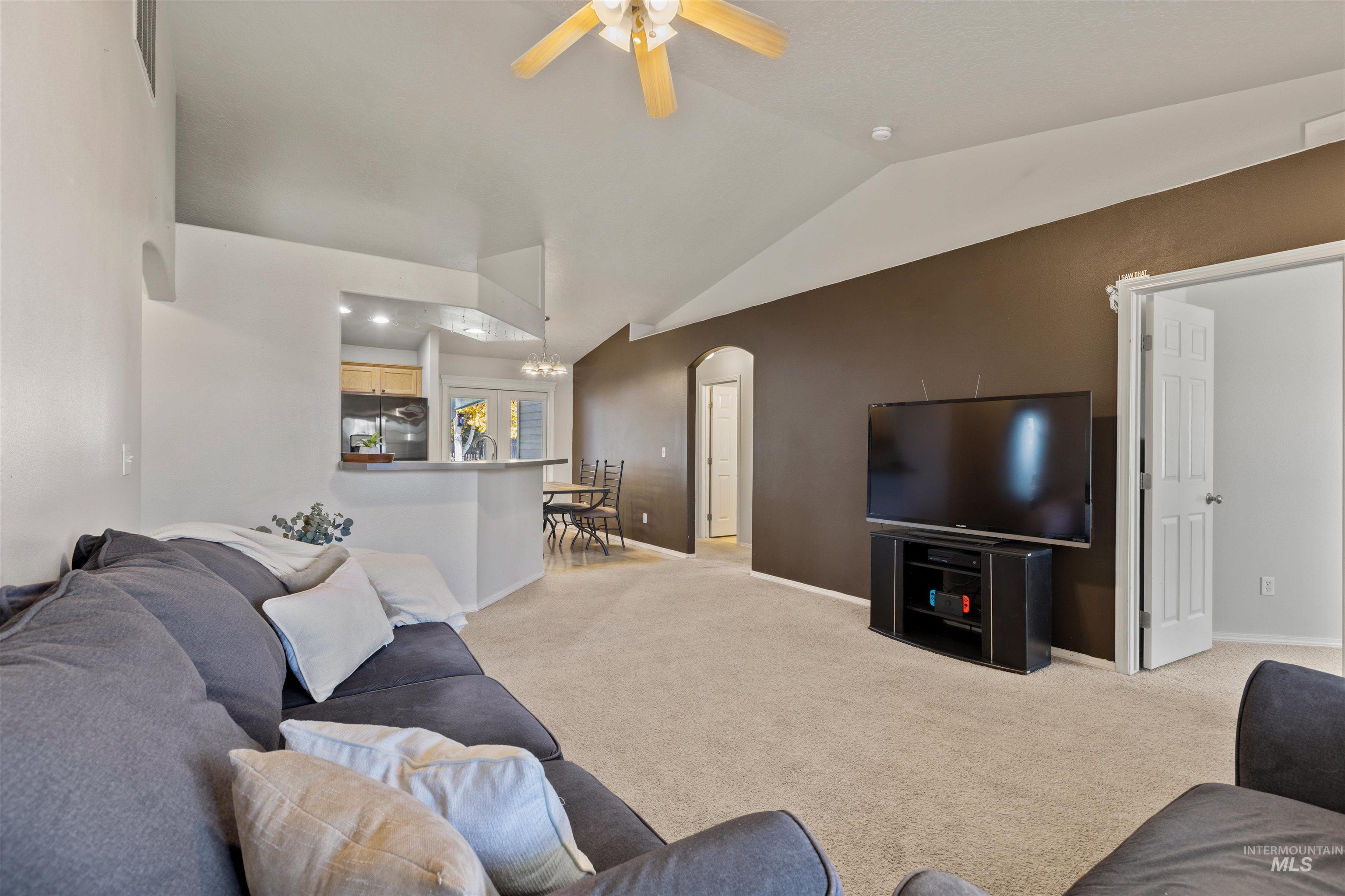 Living room with arched walkways, light carpet, lofted ceiling, and ceiling fan