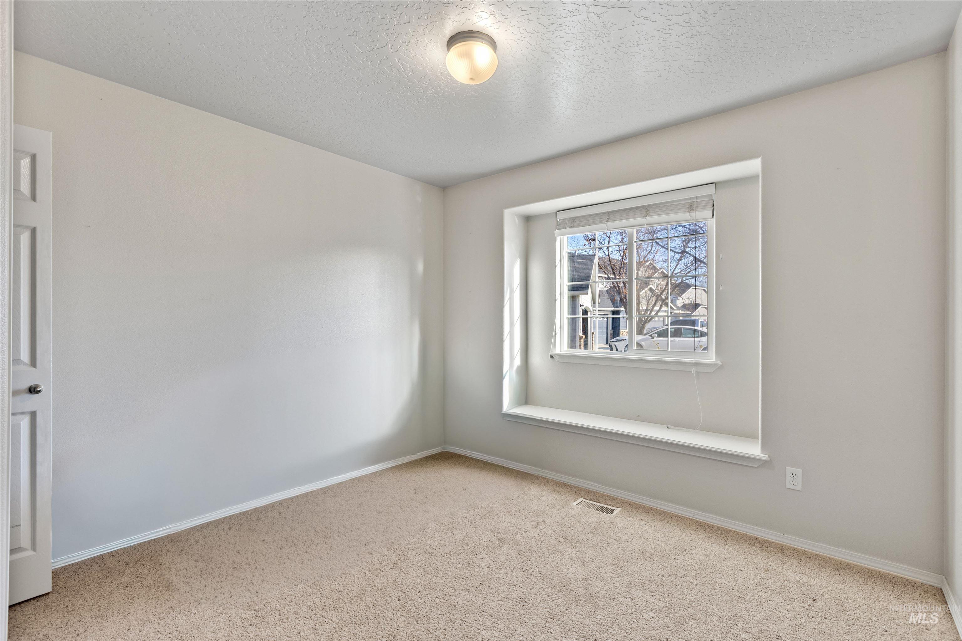 Carpeted empty room with baseboards and a textured ceiling