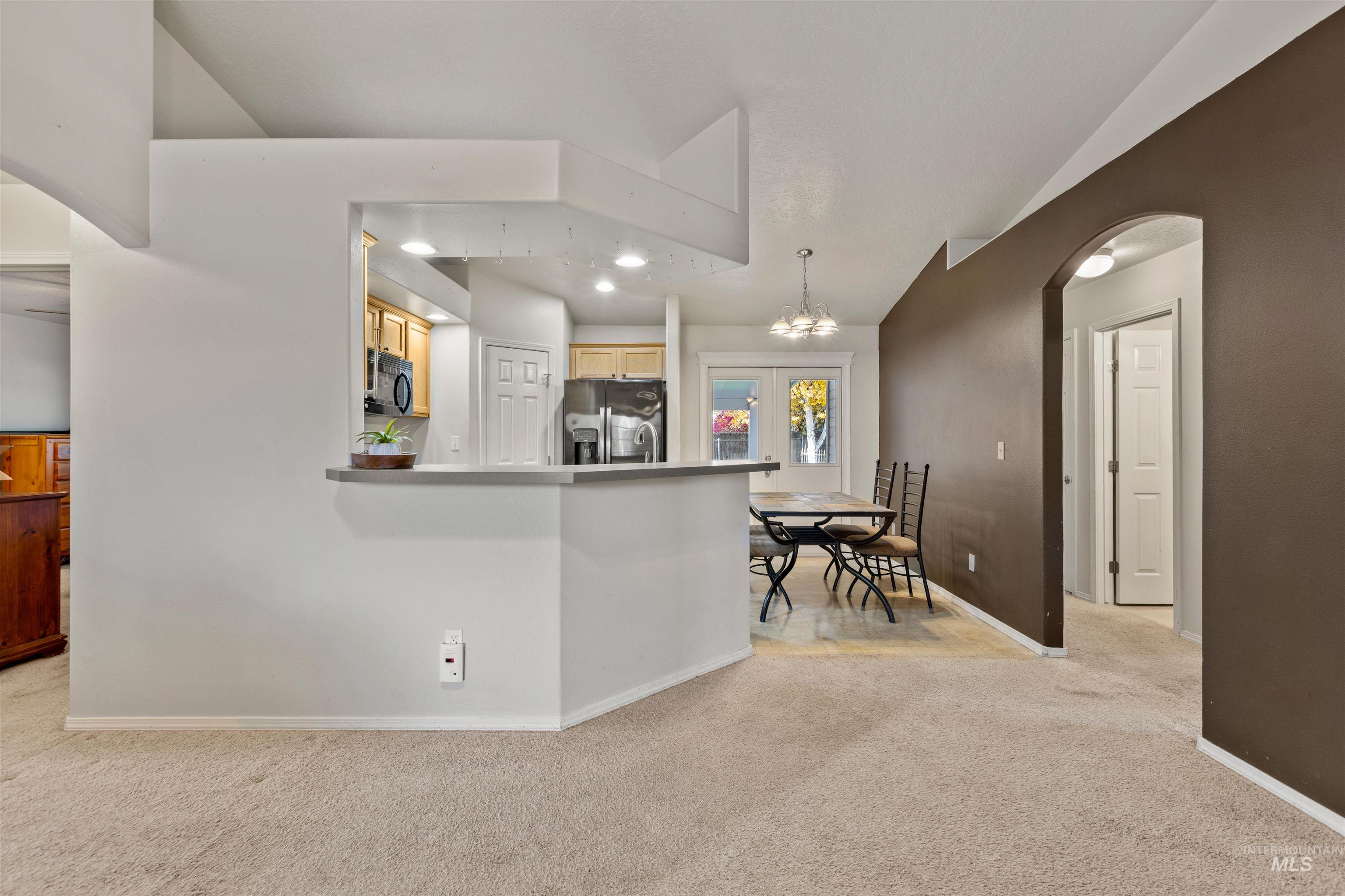 Kitchen with arched walkways, light carpet, stainless steel fridge with ice dispenser, recessed lighting, and a chandelier