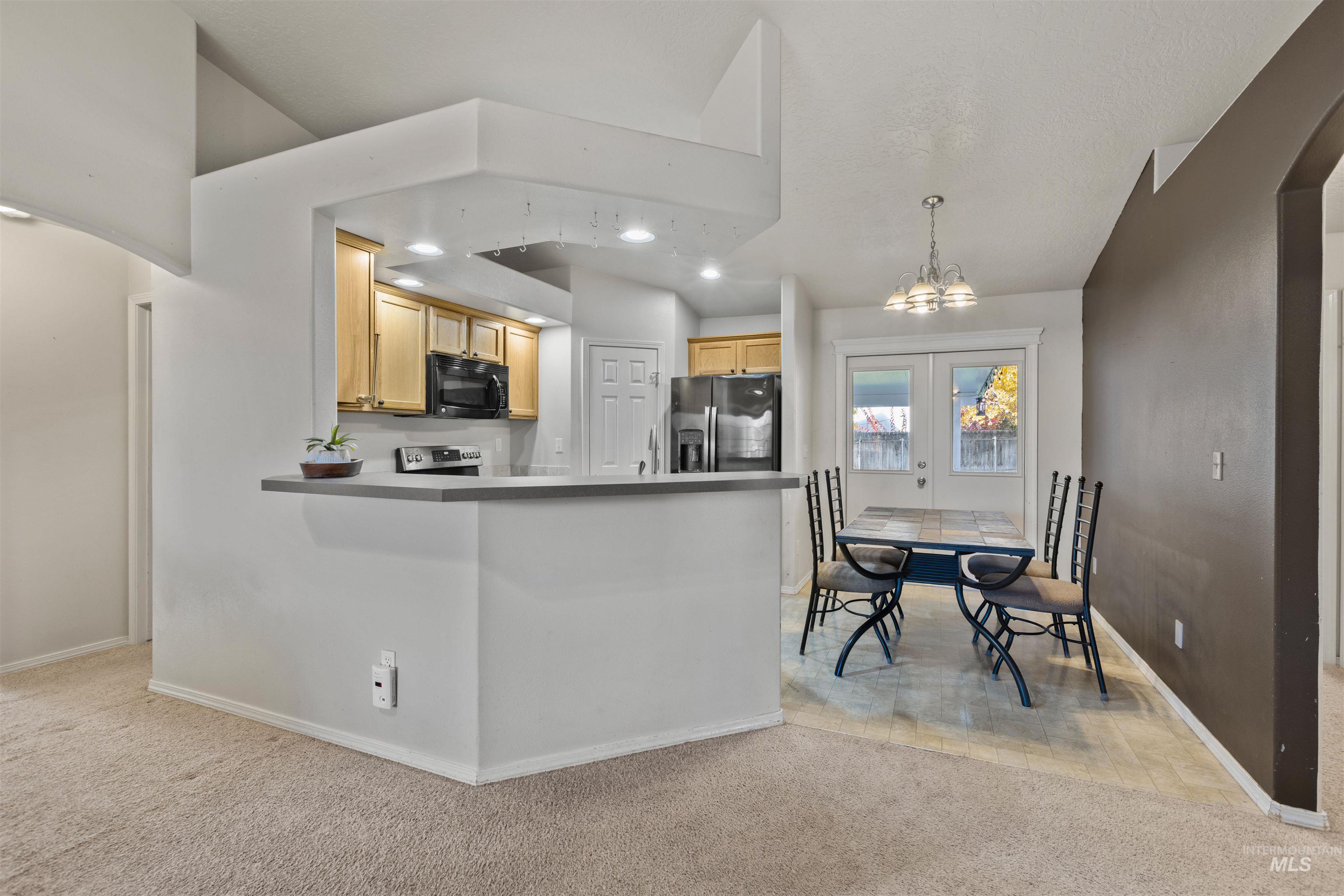 Kitchen with arched walkways, light colored carpet, recessed lighting, a chandelier, and stainless steel appliances