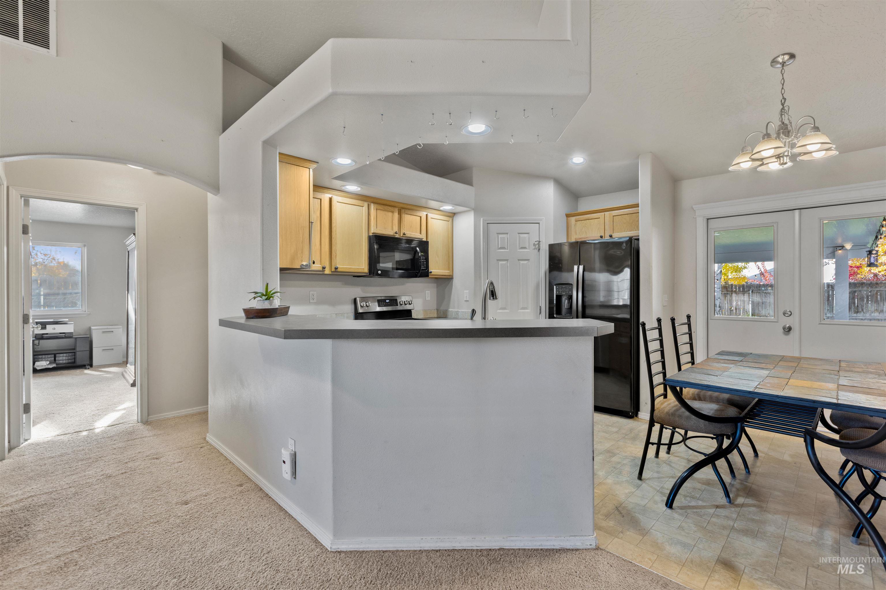 Kitchen featuring recessed lighting, black appliances, arched walkways, light colored carpet, and a peninsula