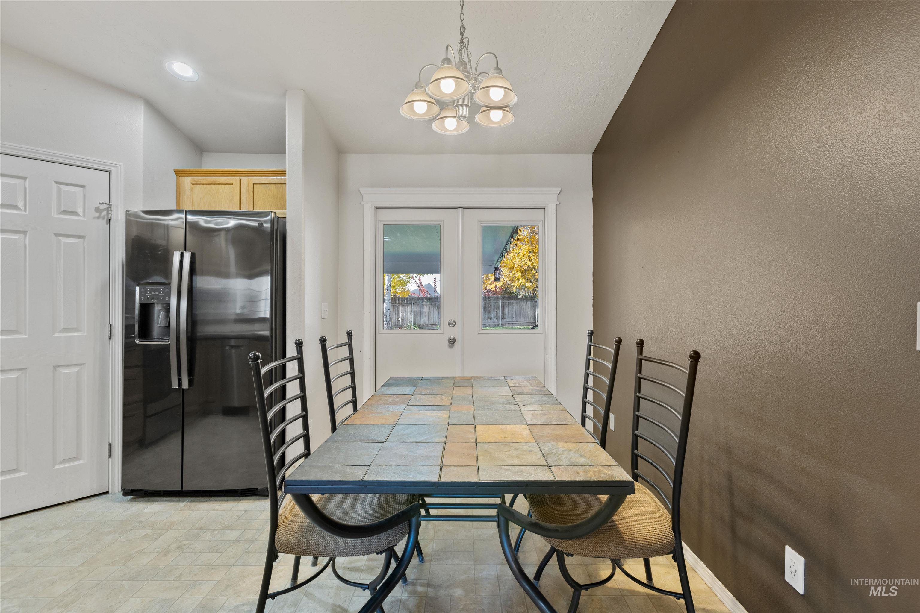 Dining room with a chandelier, french doors, recessed lighting, and a textured wall