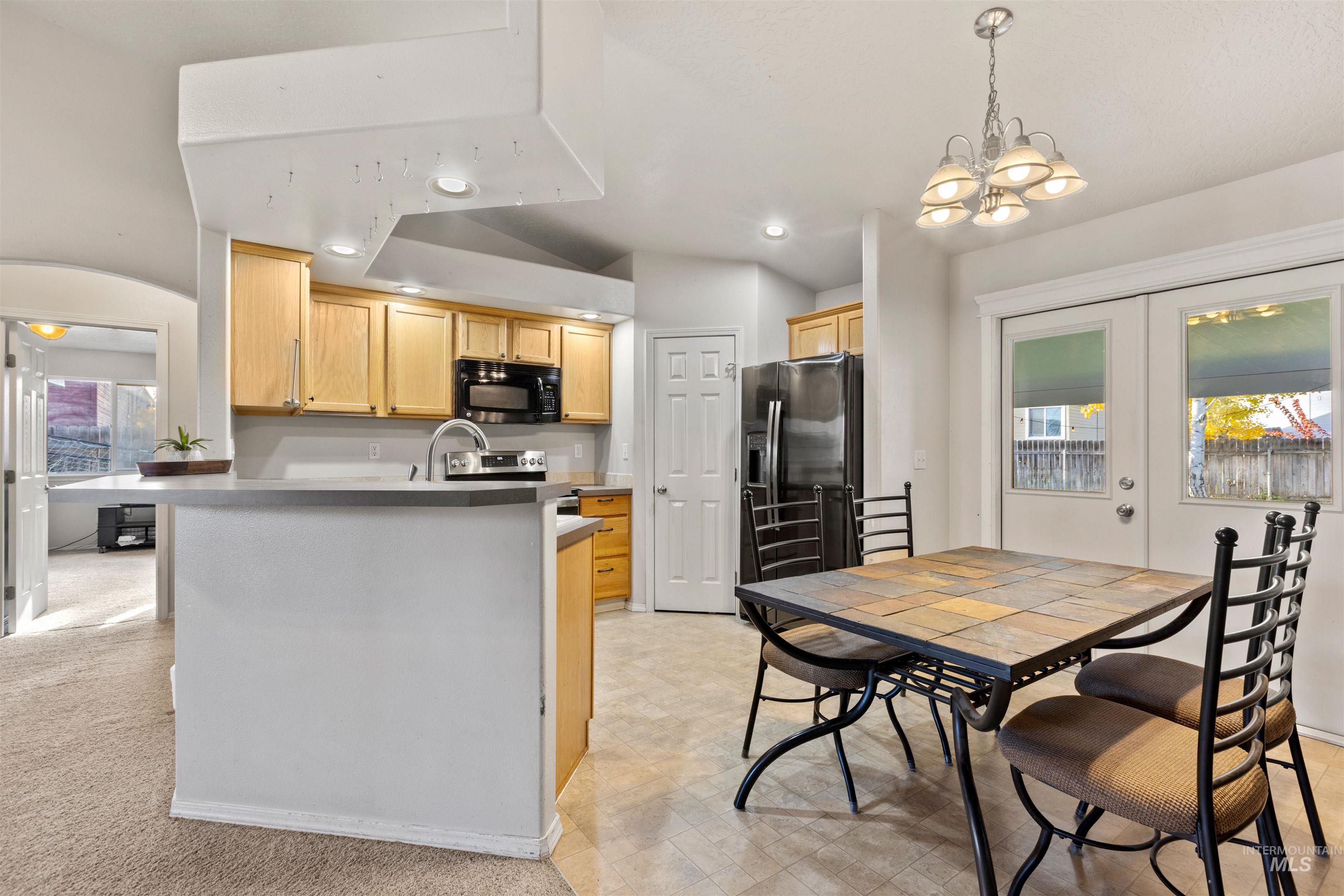 Kitchen with healthy amount of natural light, fridge with ice dispenser, black microwave, electric range, and recessed lighting
