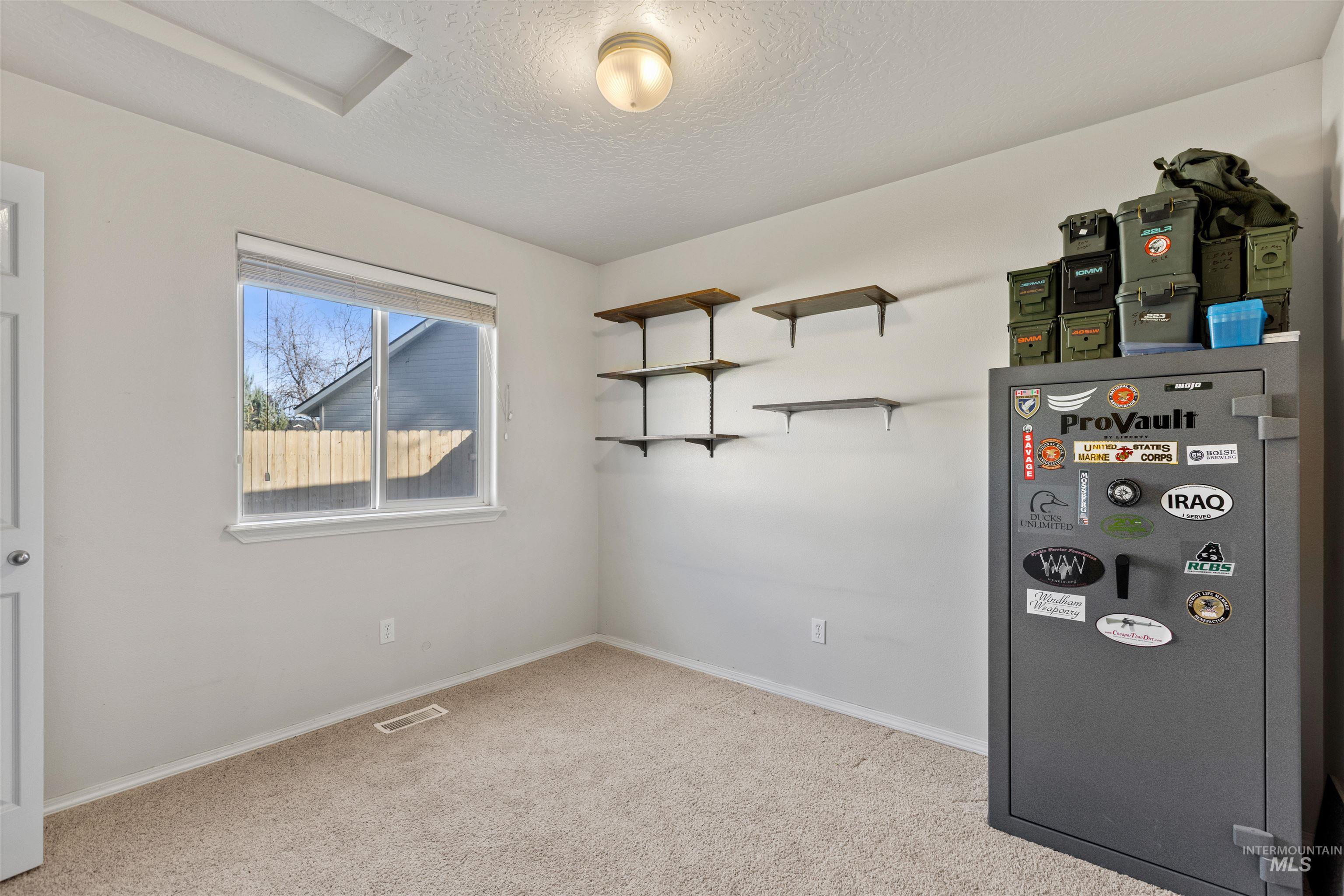 Empty room with light colored carpet, a textured ceiling, and attic access