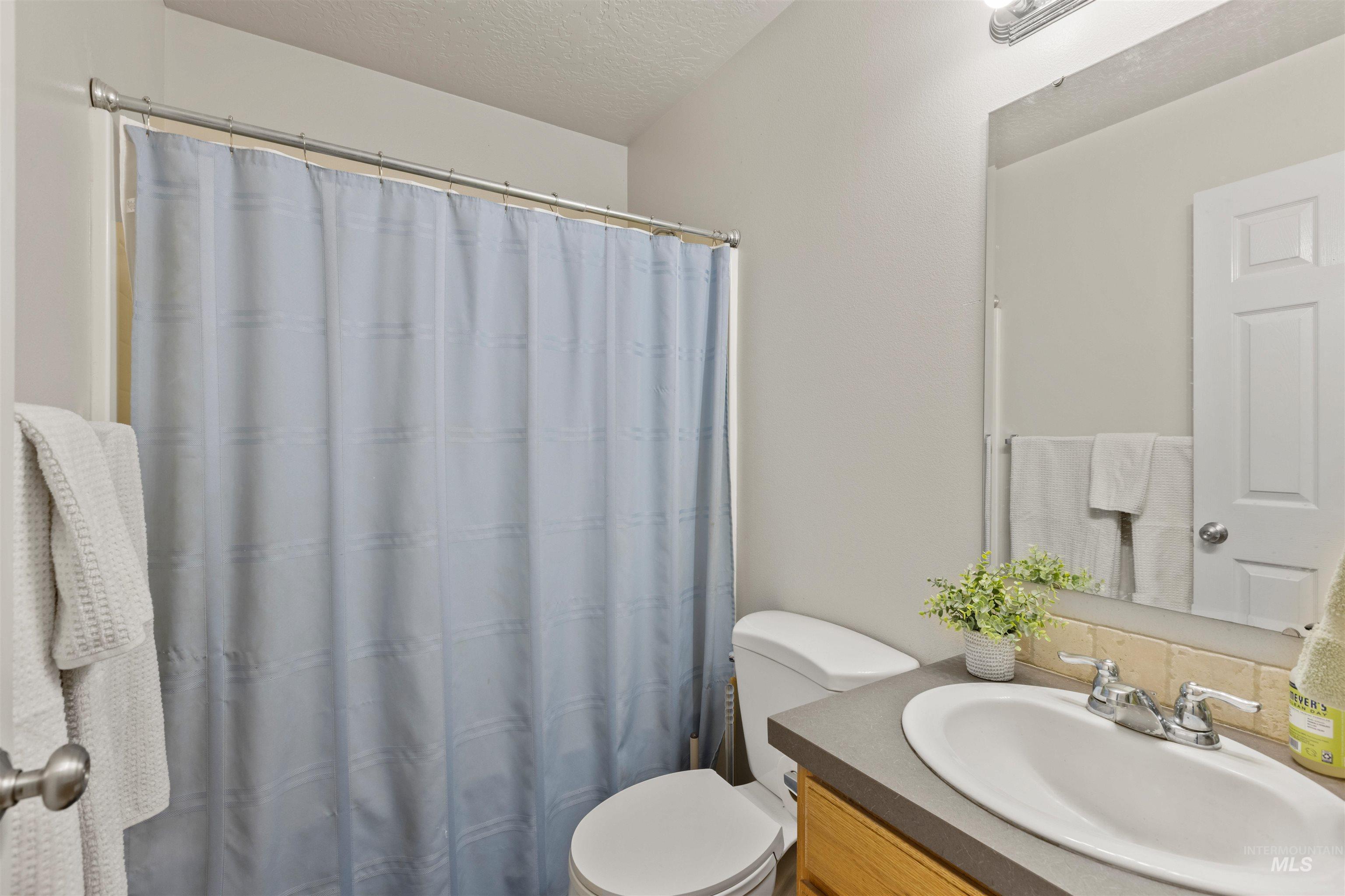 Bathroom with vanity, a shower with shower curtain, and a textured ceiling