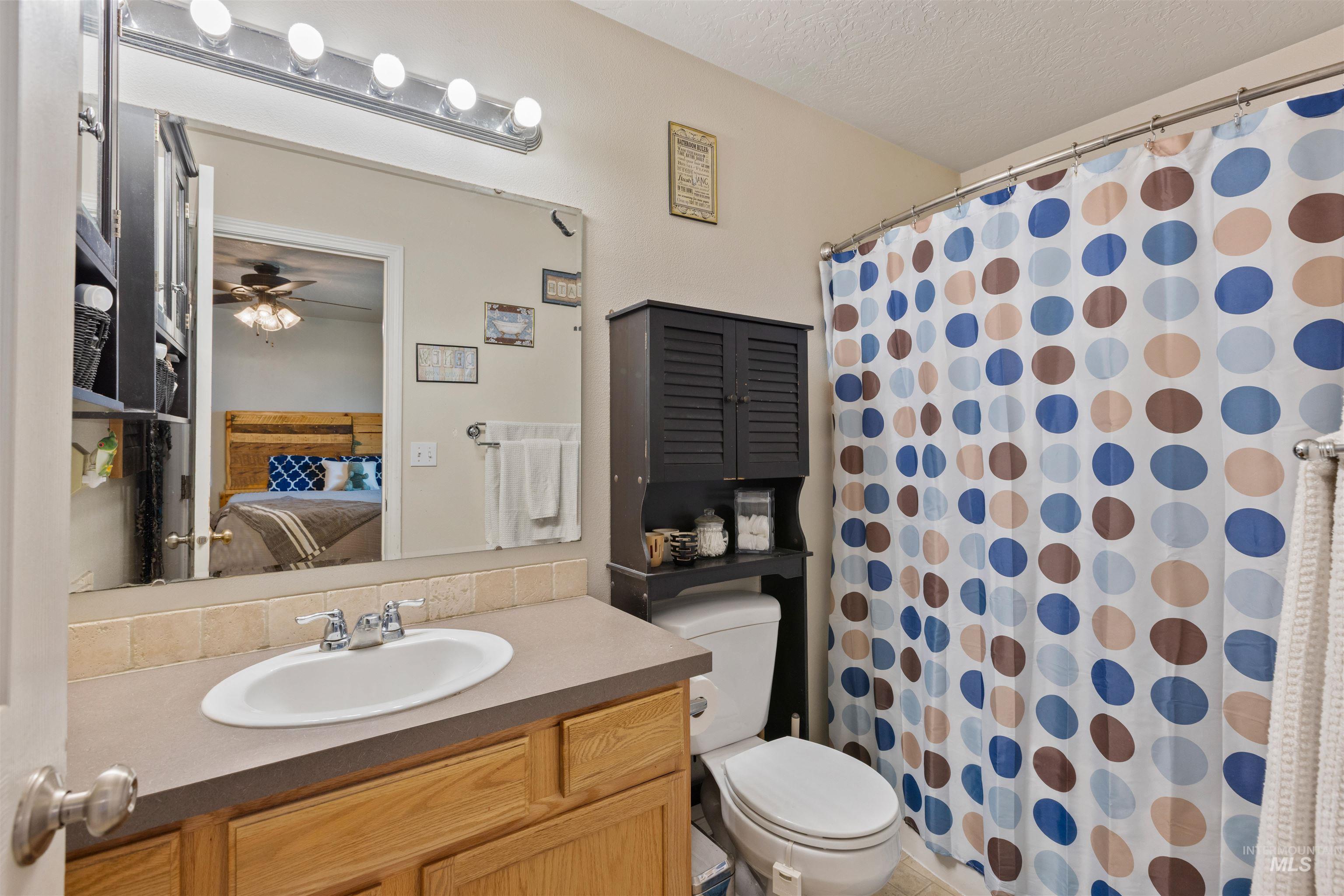 Ensuite bathroom featuring vanity, a shower with shower curtain, and a textured ceiling