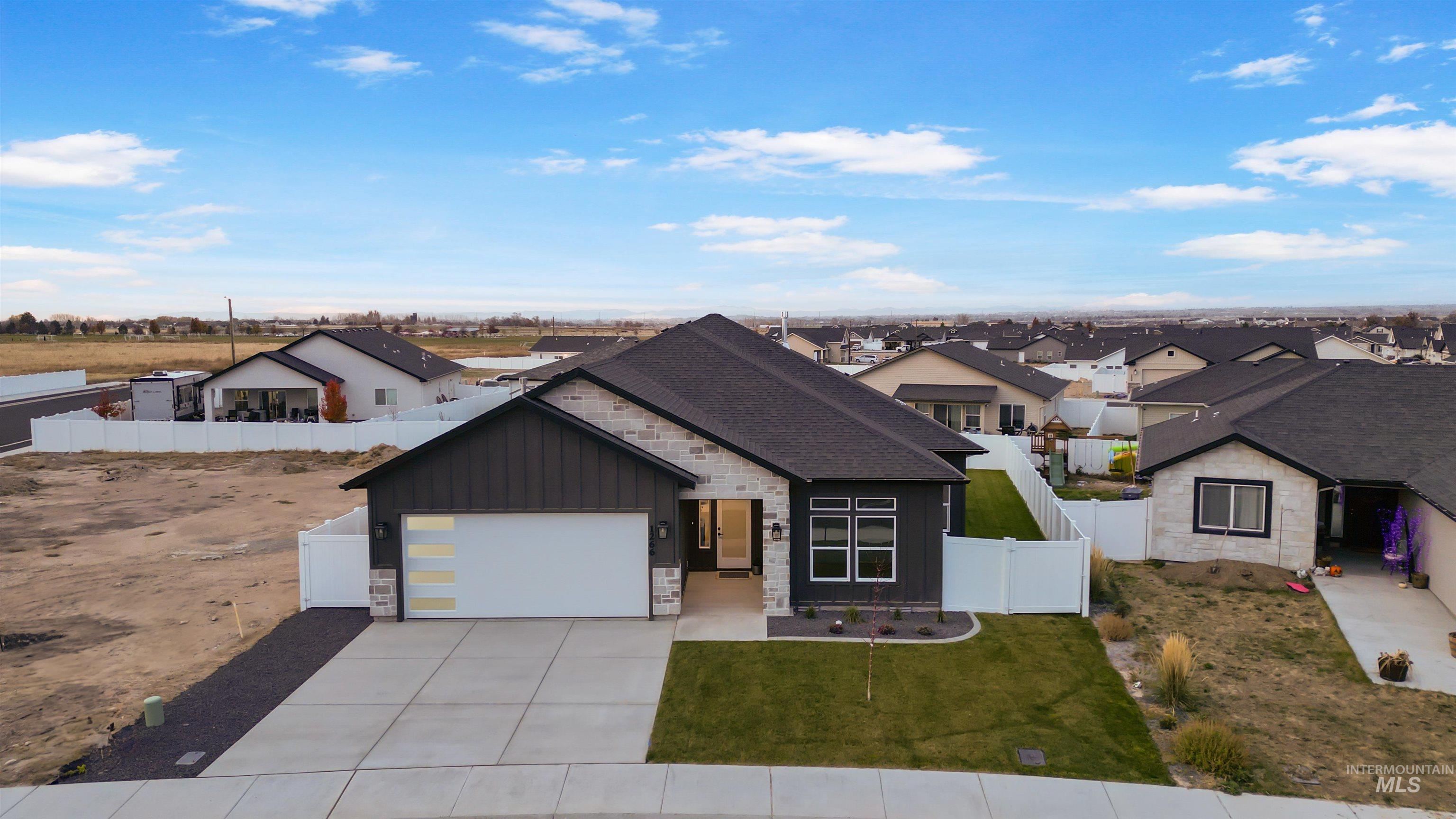 View of front of house with stone siding, driveway, board and batten siding, a residential view, and an attached garage