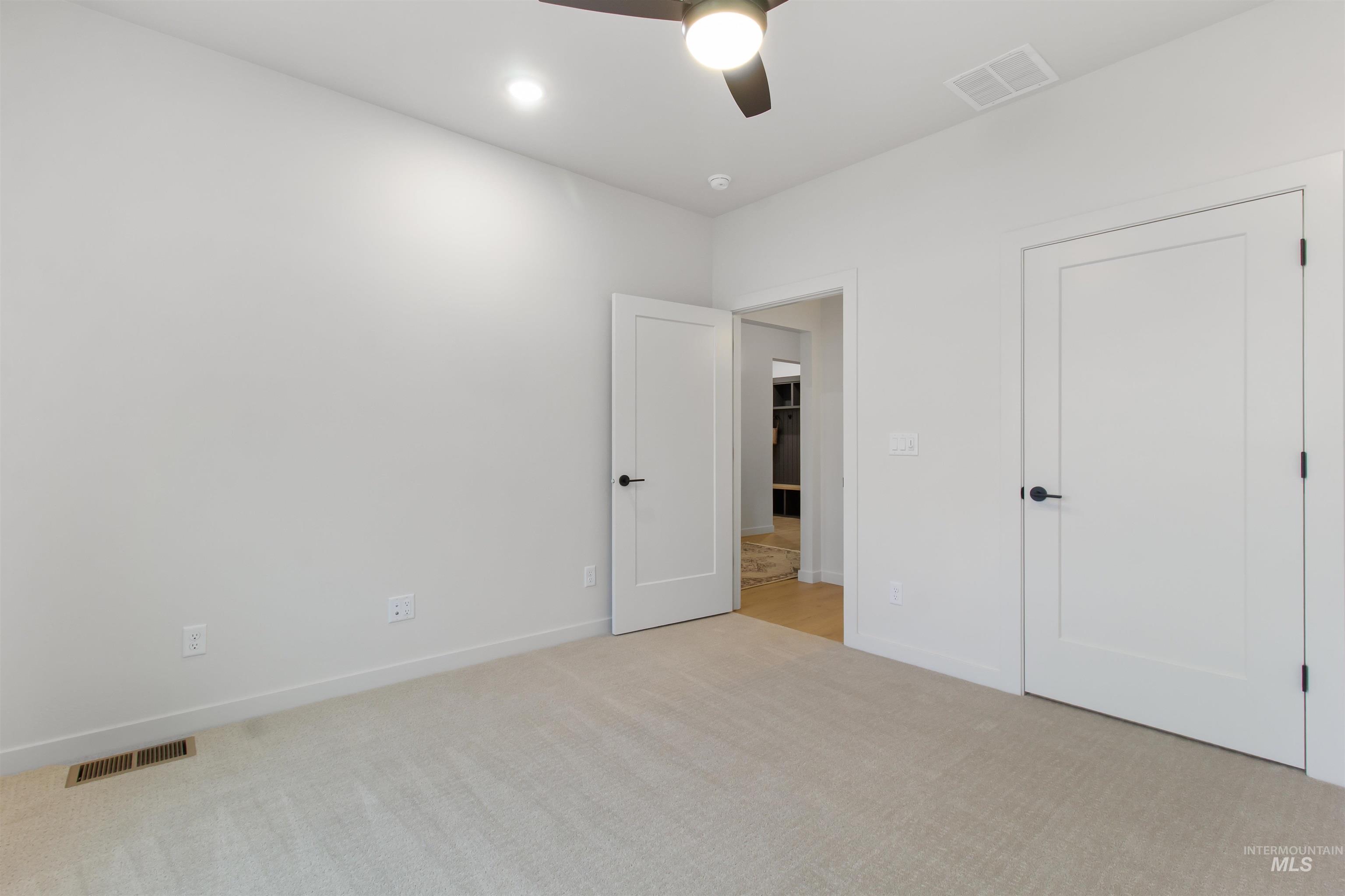Unfurnished bedroom featuring light carpet and a ceiling fan