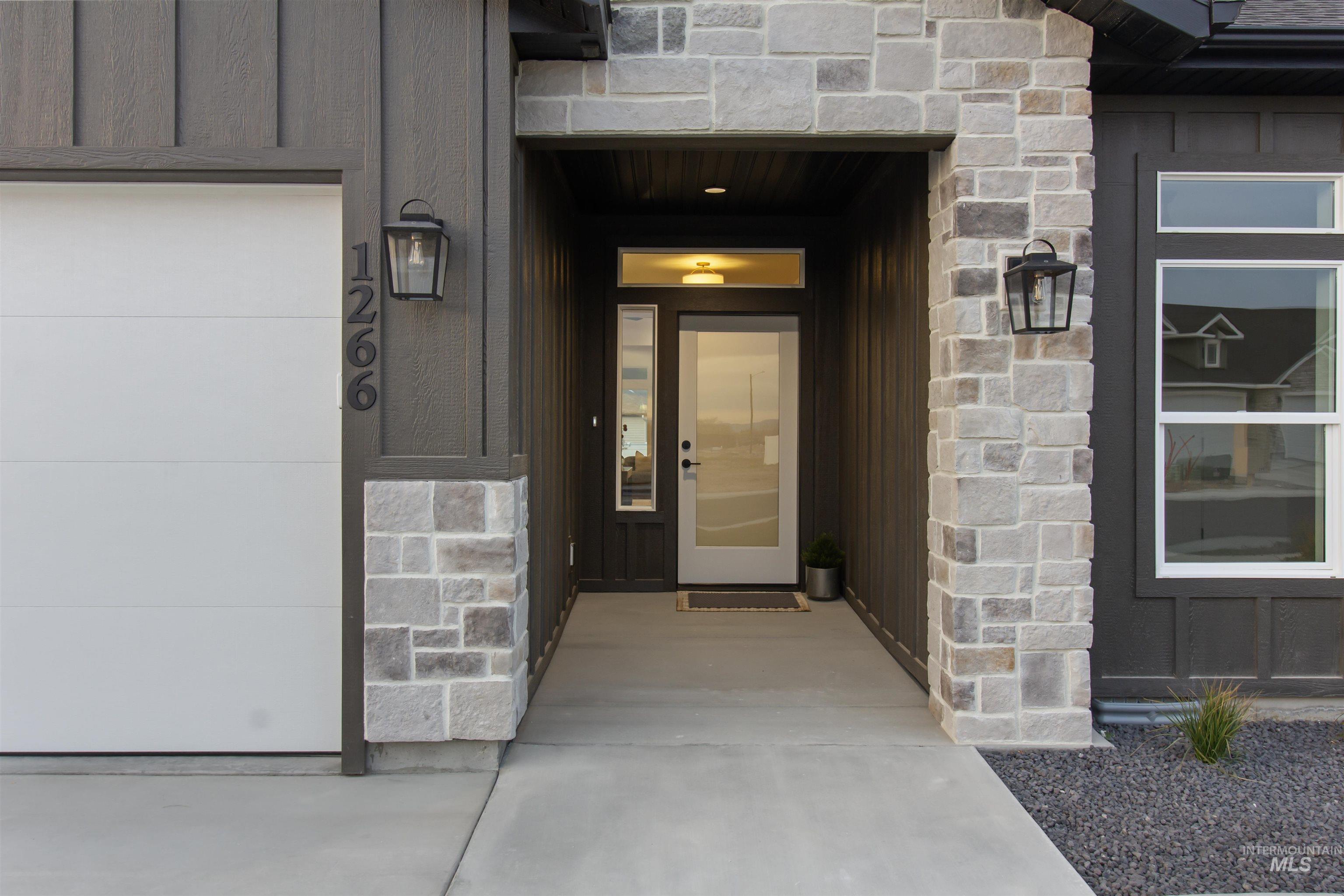 Doorway to property featuring stone siding, board and batten siding, and a garage