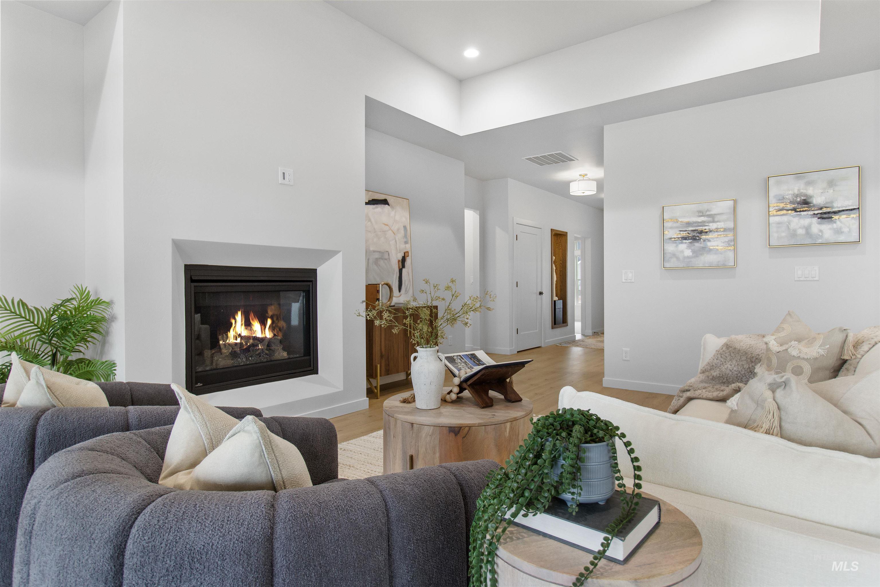 Living room with a glass covered fireplace, wood finished floors, and recessed lighting