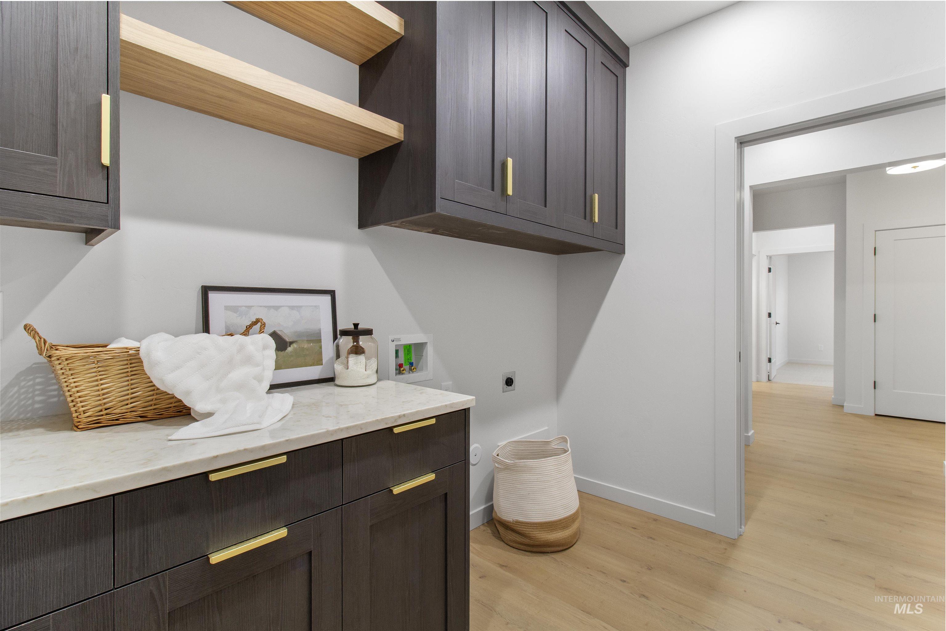 Laundry room with cabinet space, light wood finished floors, hookup for a washing machine, and electric dryer hookup