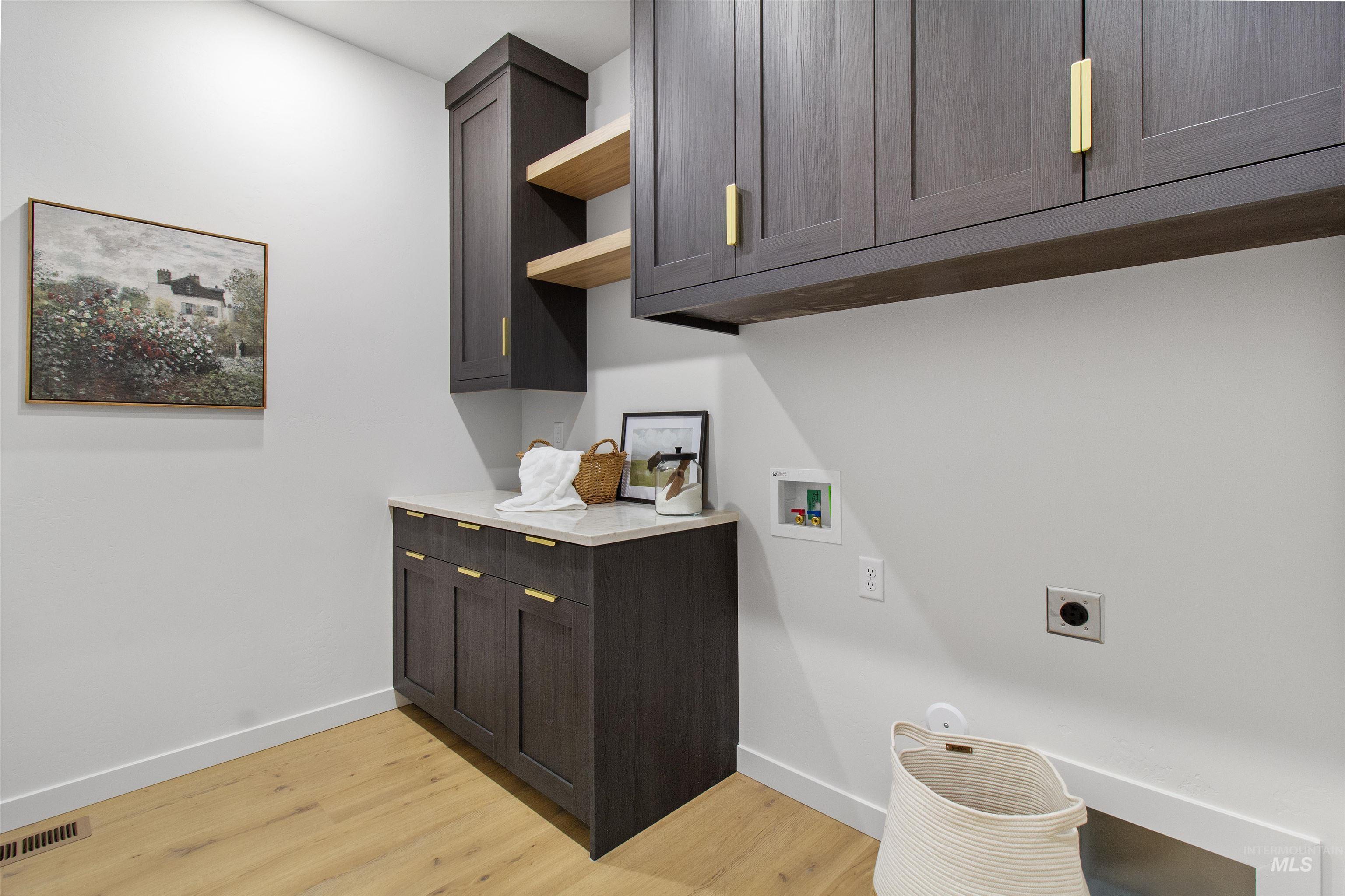 Laundry room featuring light wood-type flooring, washer hookup, hookup for an electric dryer, and cabinet space