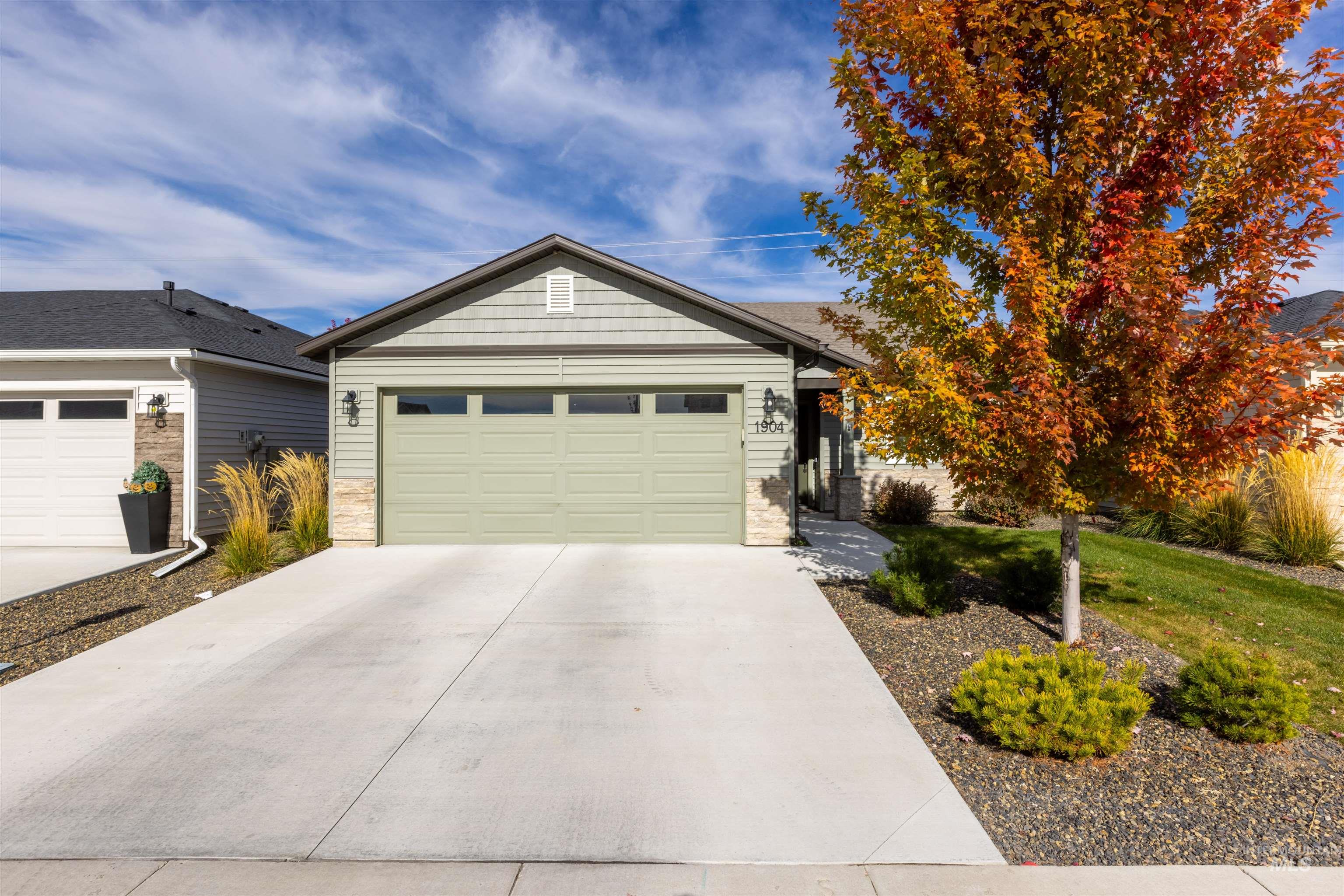 Ranch-style house with driveway, an attached garage, stone siding, and a front yard