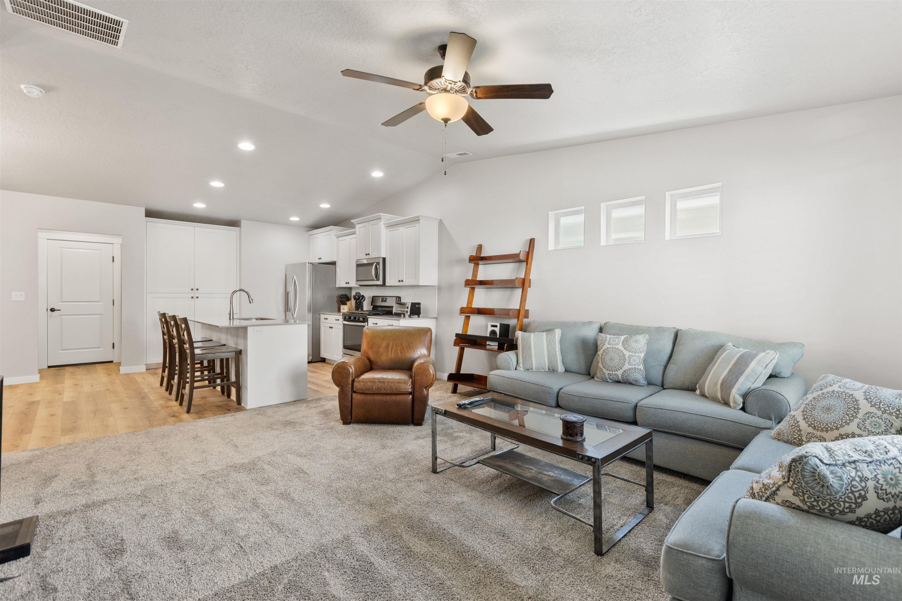 Living area featuring vaulted ceiling, recessed lighting, light wood-style floors, a ceiling fan, and light carpet