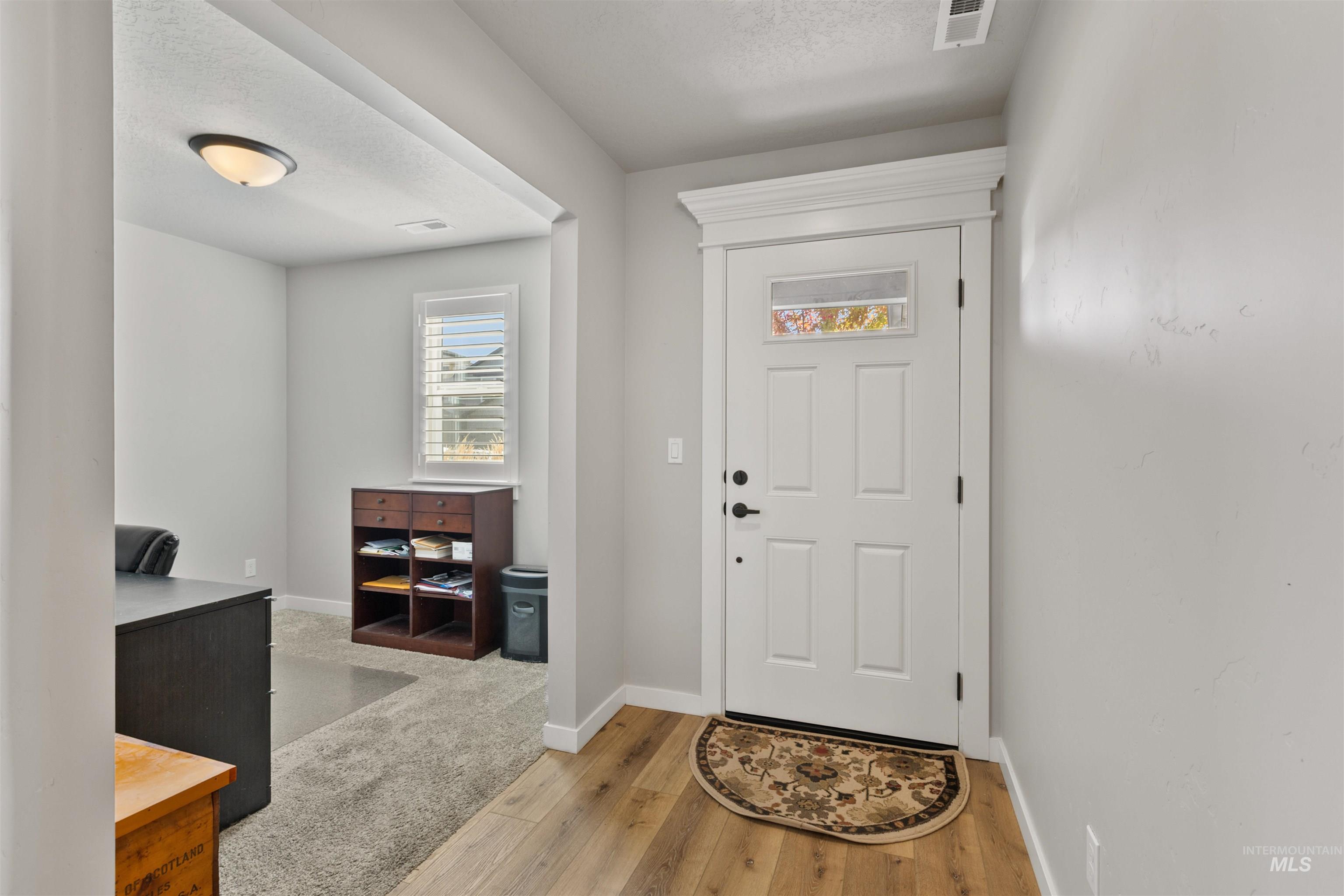 Foyer with light wood finished floors and a textured ceiling