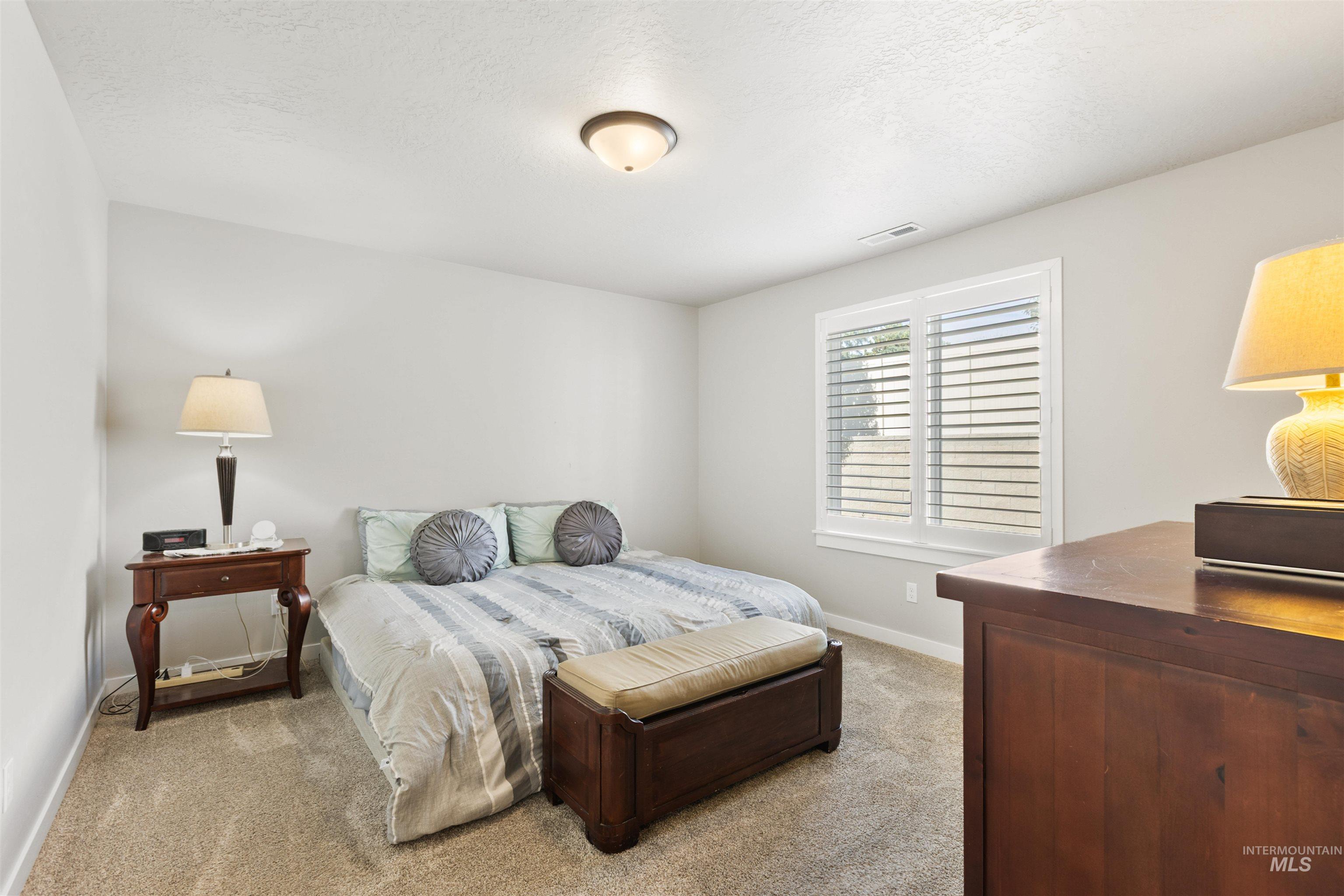 Bedroom with light carpet and a textured ceiling