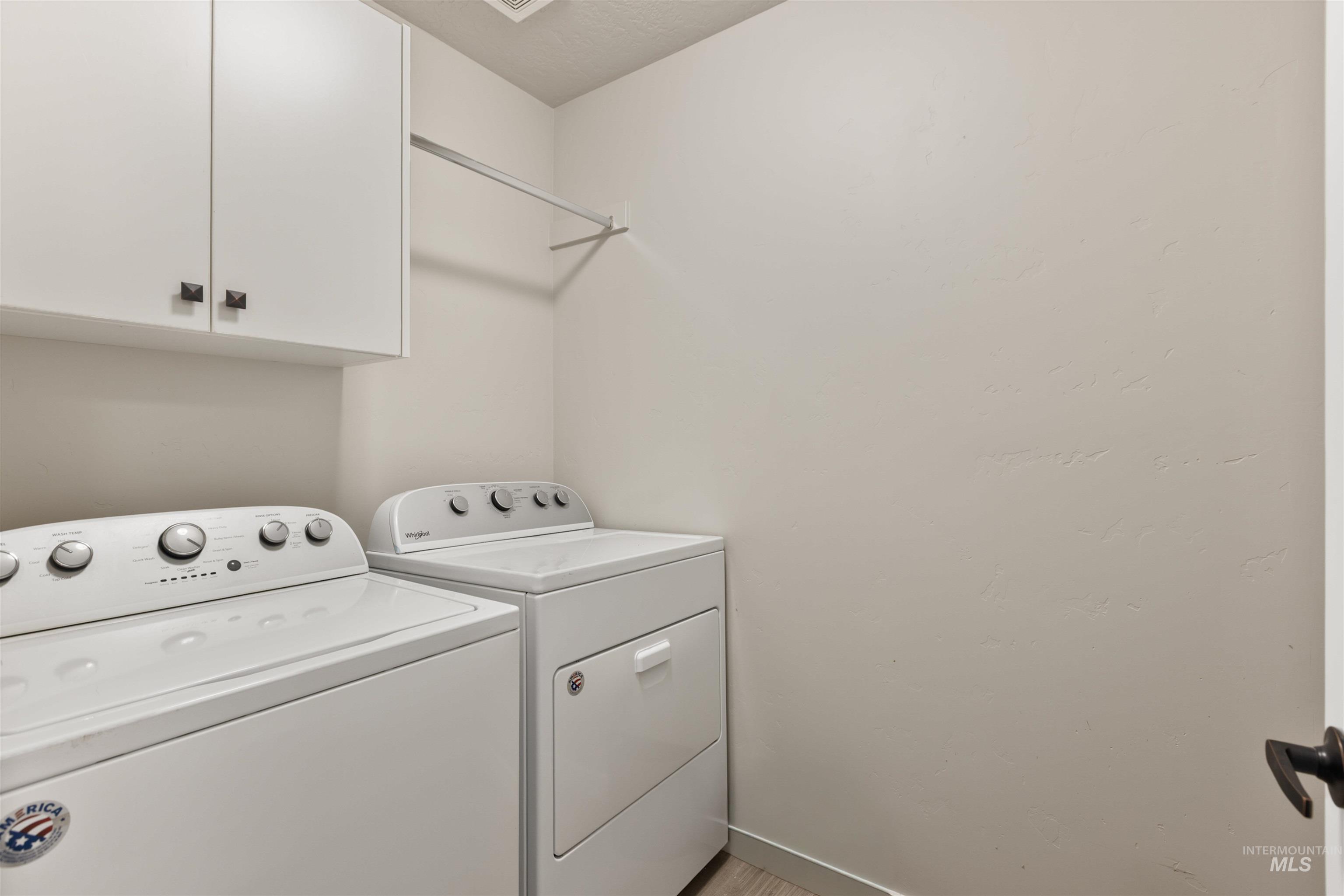 Laundry room with separate washer and dryer and cabinet space