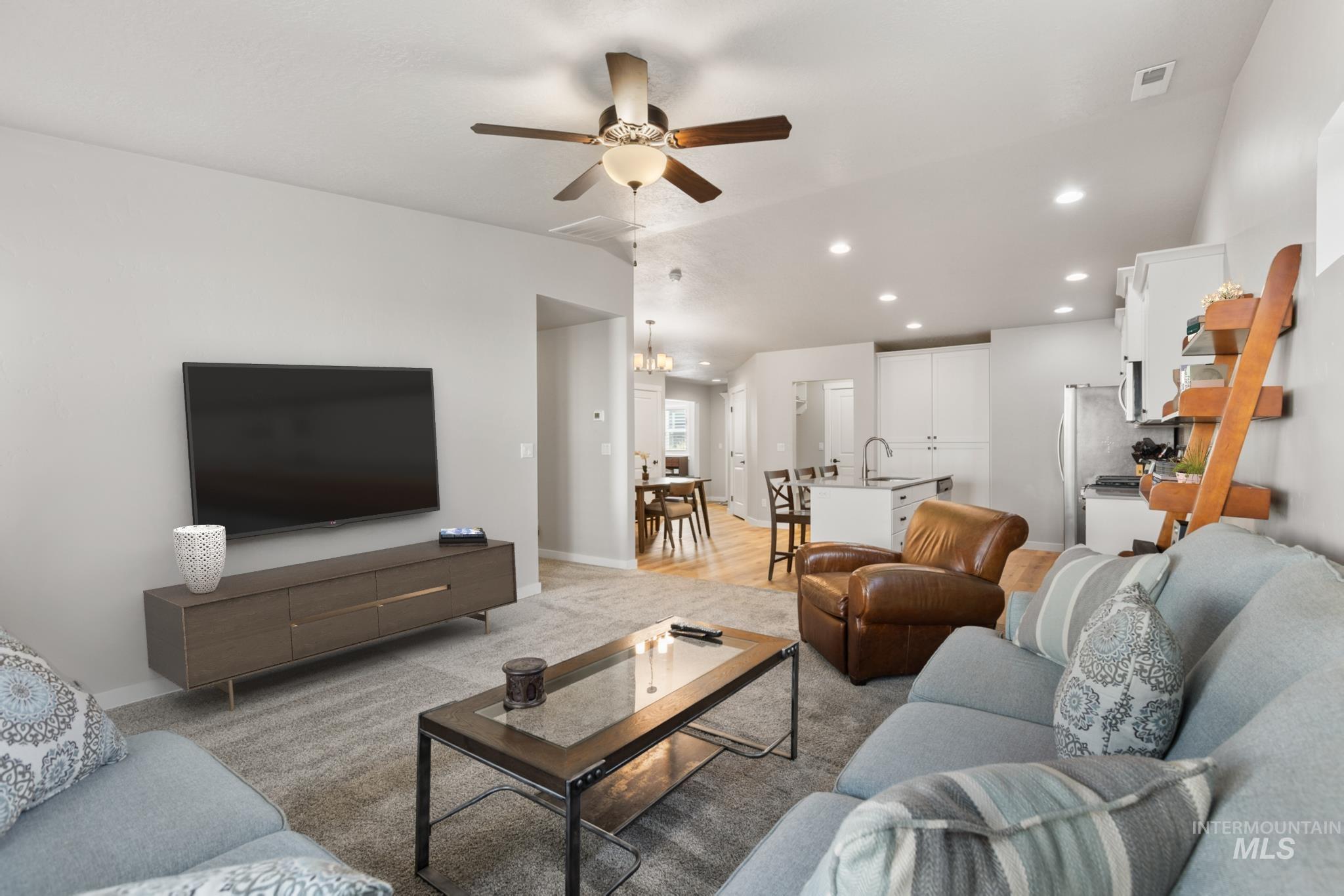 Living room featuring lofted ceiling, a ceiling fan, recessed lighting, light colored carpet, and a chandelier
