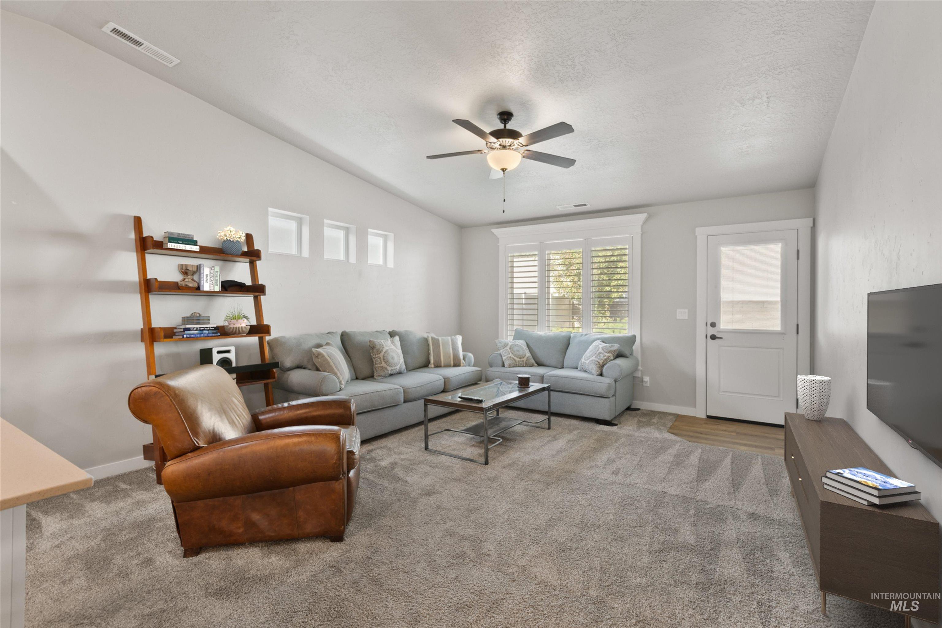 Living area with carpet, a ceiling fan, and a textured ceiling