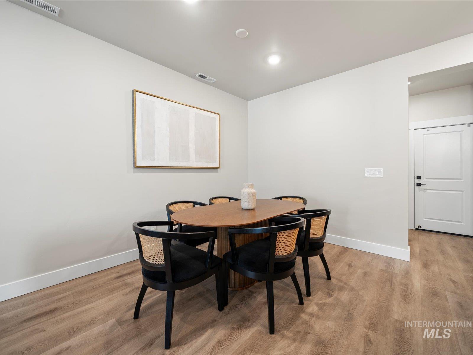 Dining space with light wood finished floors and recessed lighting