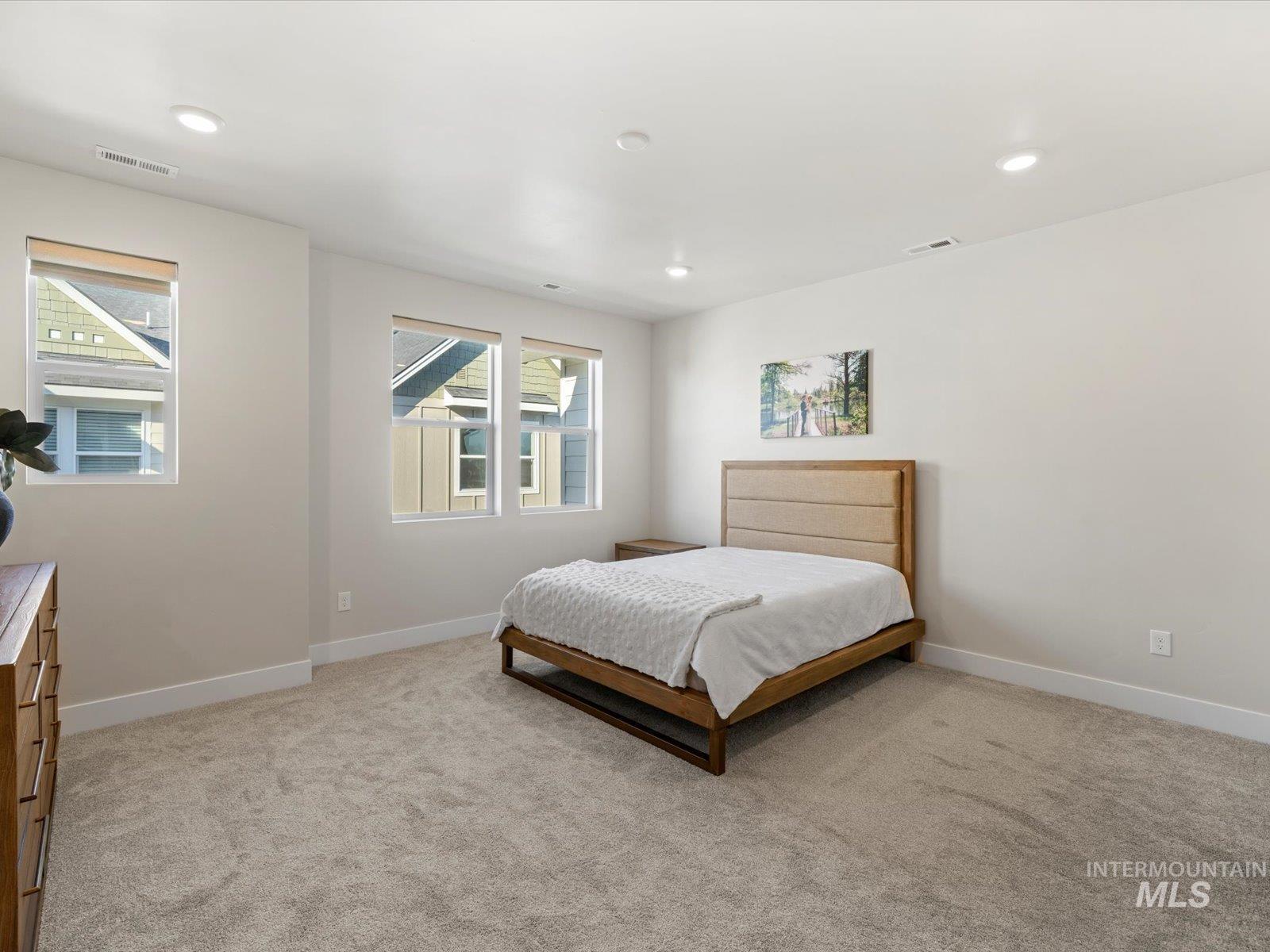 Bedroom with light colored carpet and recessed lighting