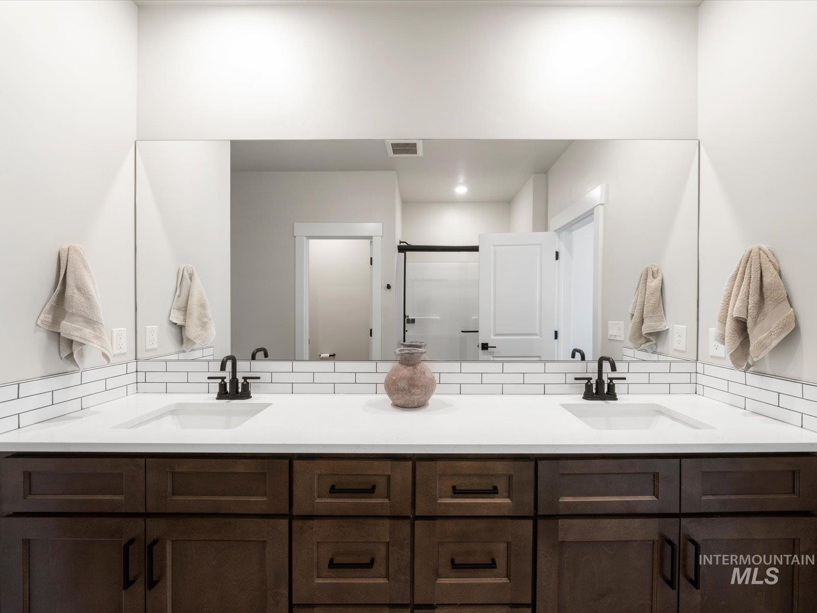 Bathroom featuring double vanity, a shower stall, and tasteful backsplash